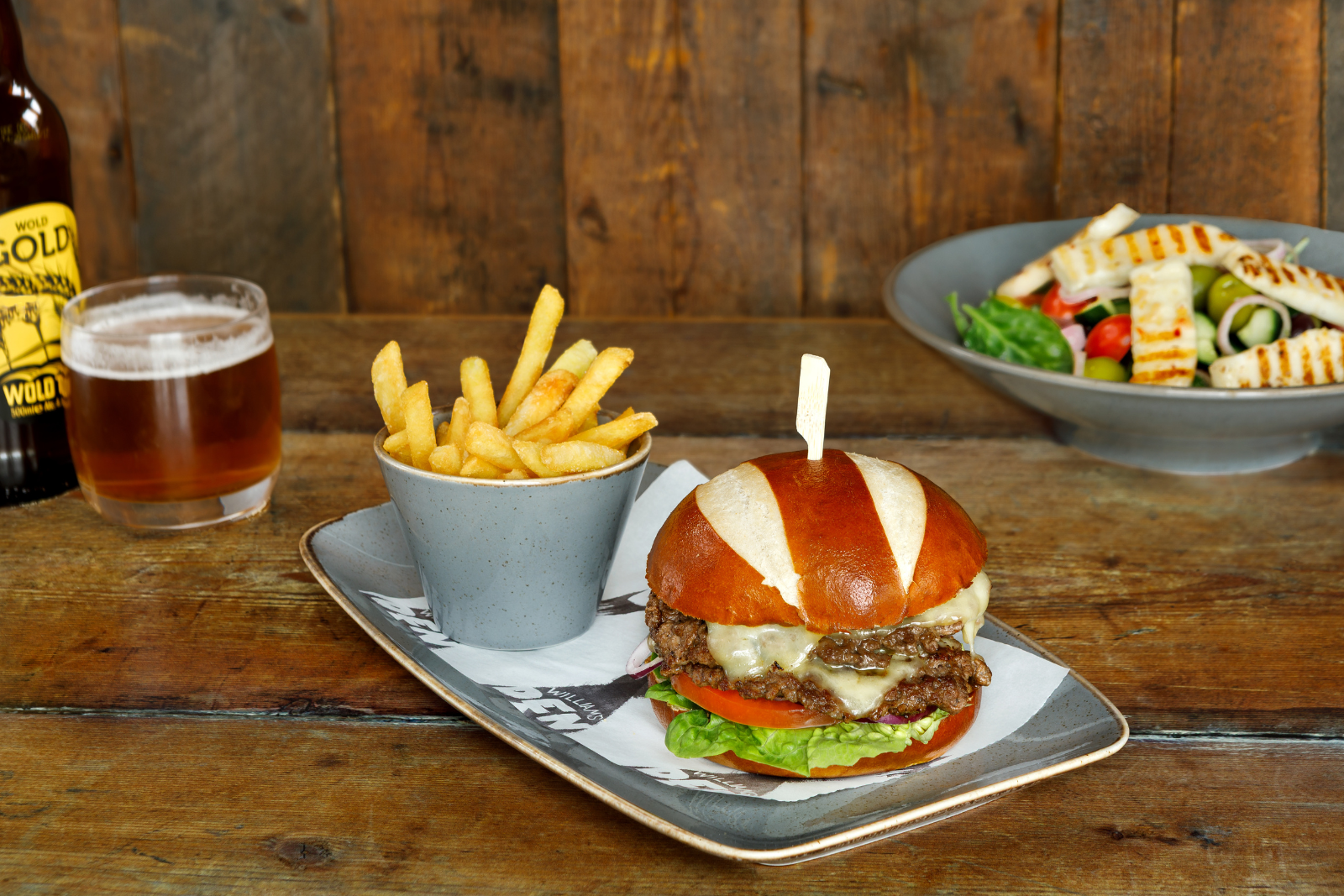 Gourmet cheeseburger with chips and salad on rustic table