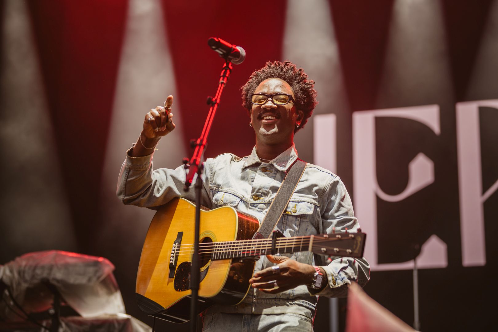Smiling musician with guitar on stage under bright lights