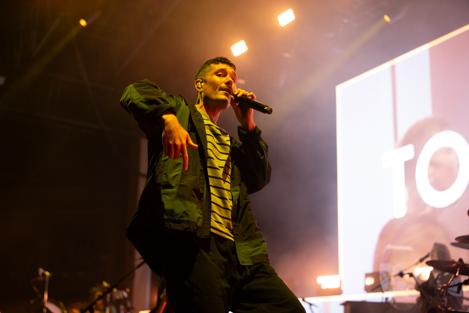 Singer performing energetically on stage with vibrant lighting