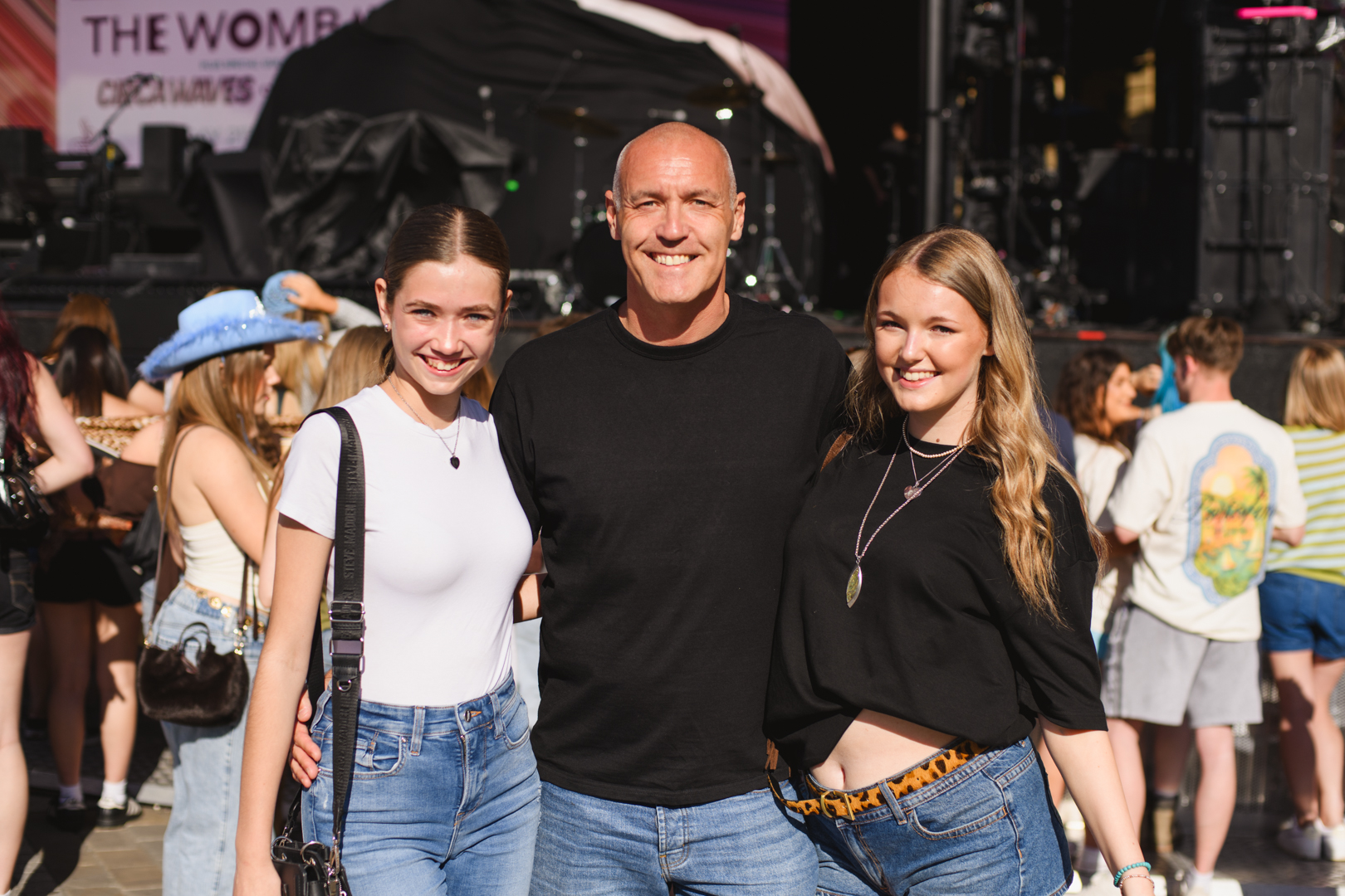 Smiling group at outdoor music festival with stage background