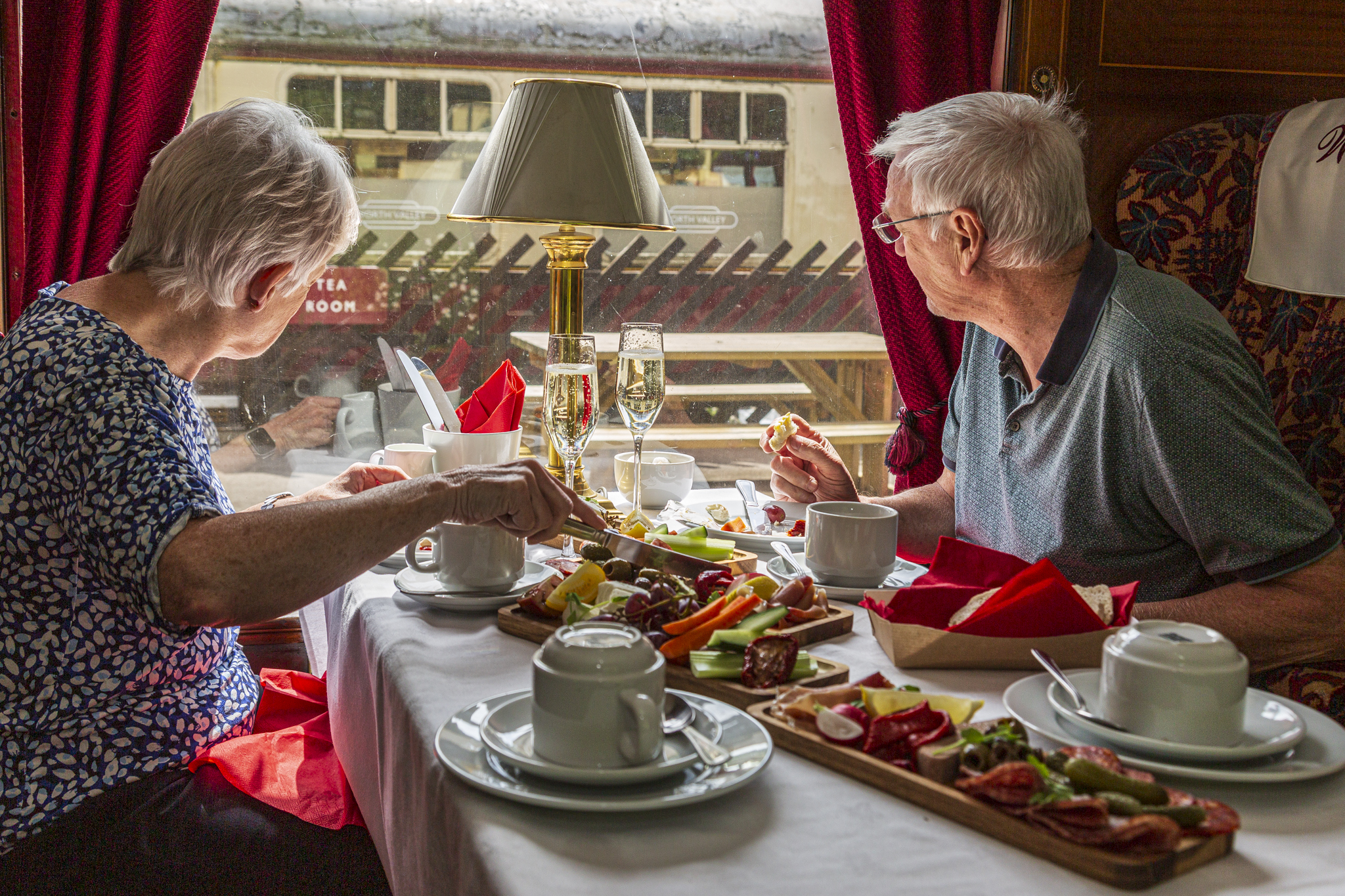 Elderly couple dining on a vintage train with scenic view