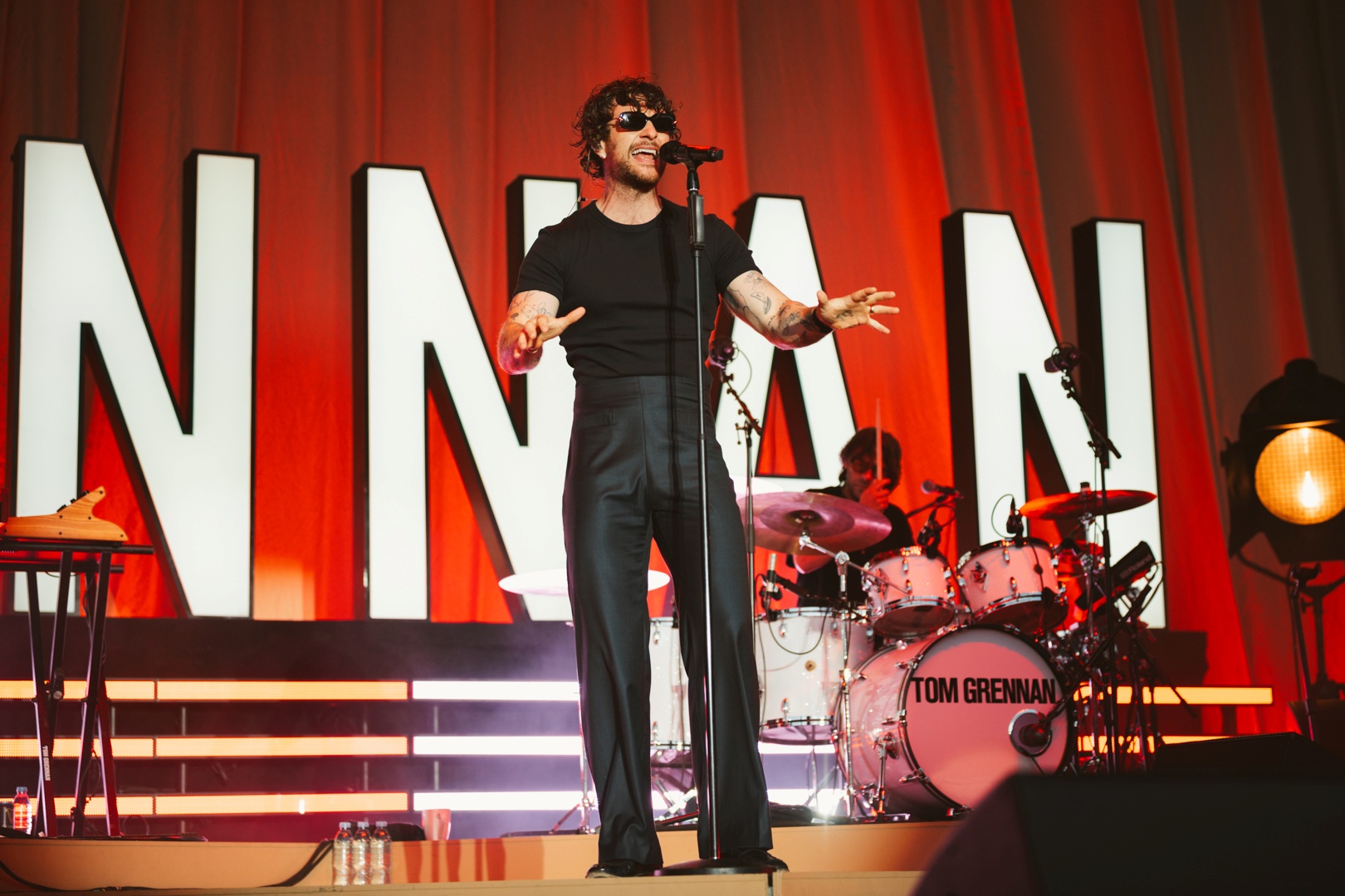 Singer performing on stage with red lighting and large letters