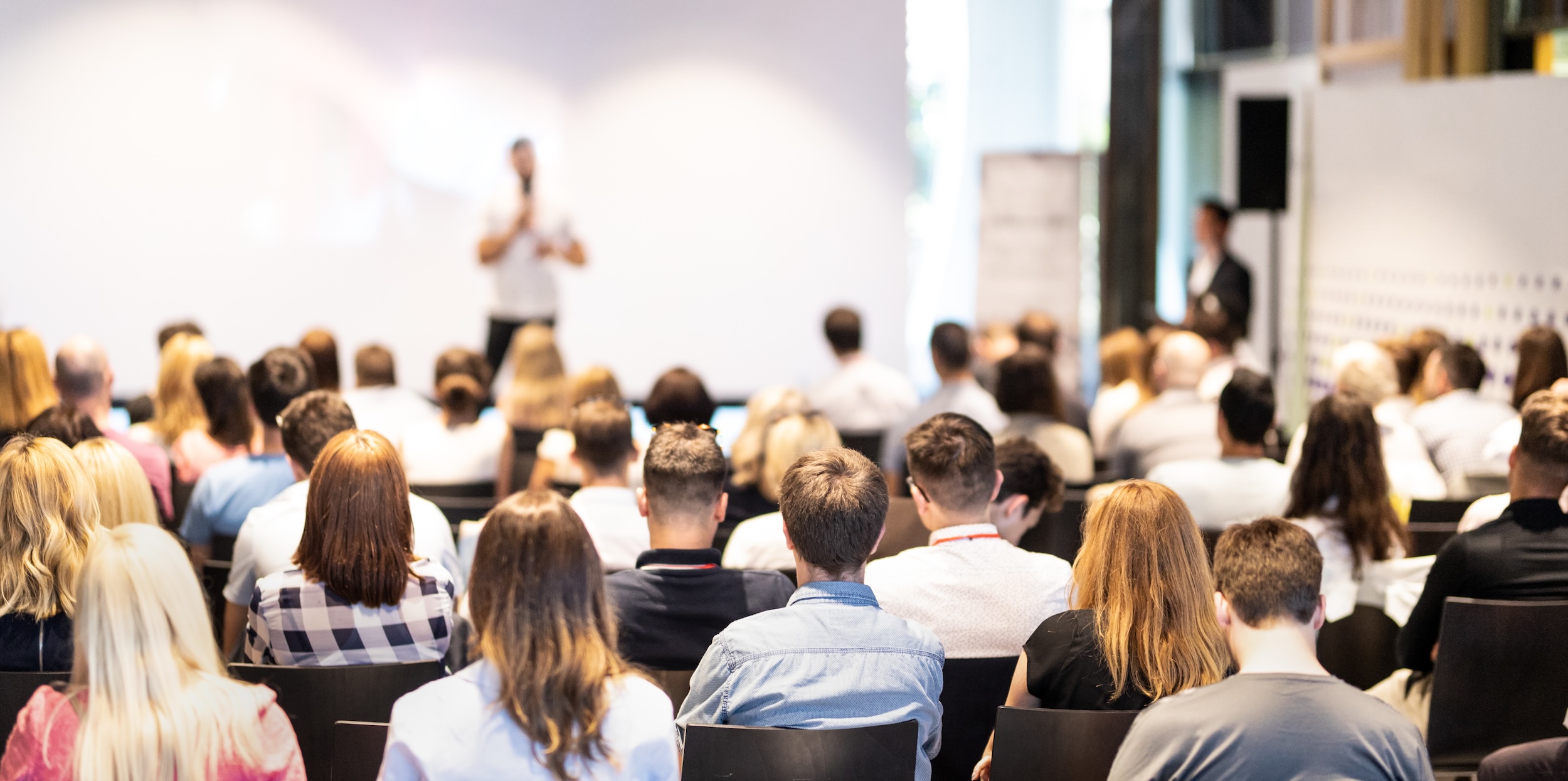 Audience seated in a conference room listening to a speaker
