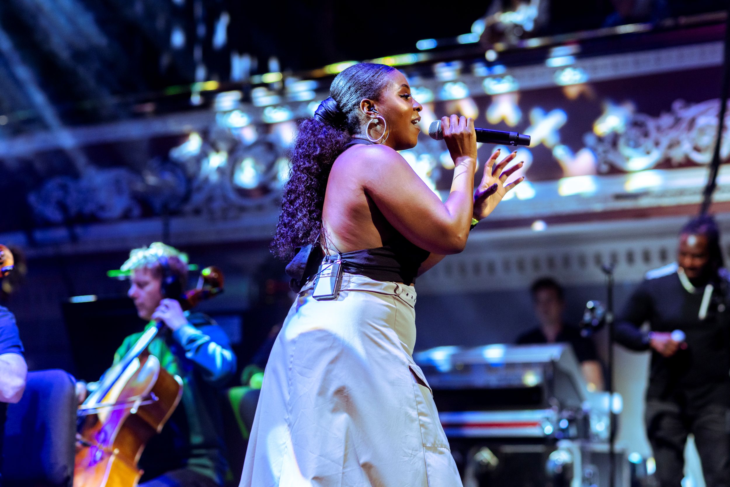 Singer performing on stage with orchestra and colorful lights