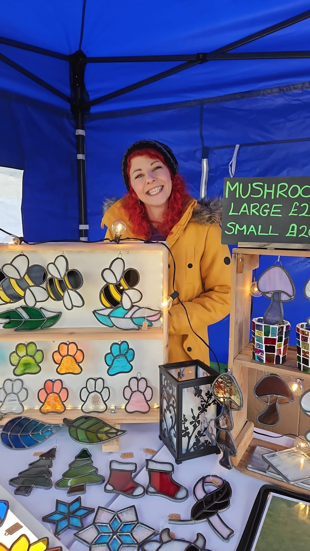 Smiling vendor at market stall with stained glass art