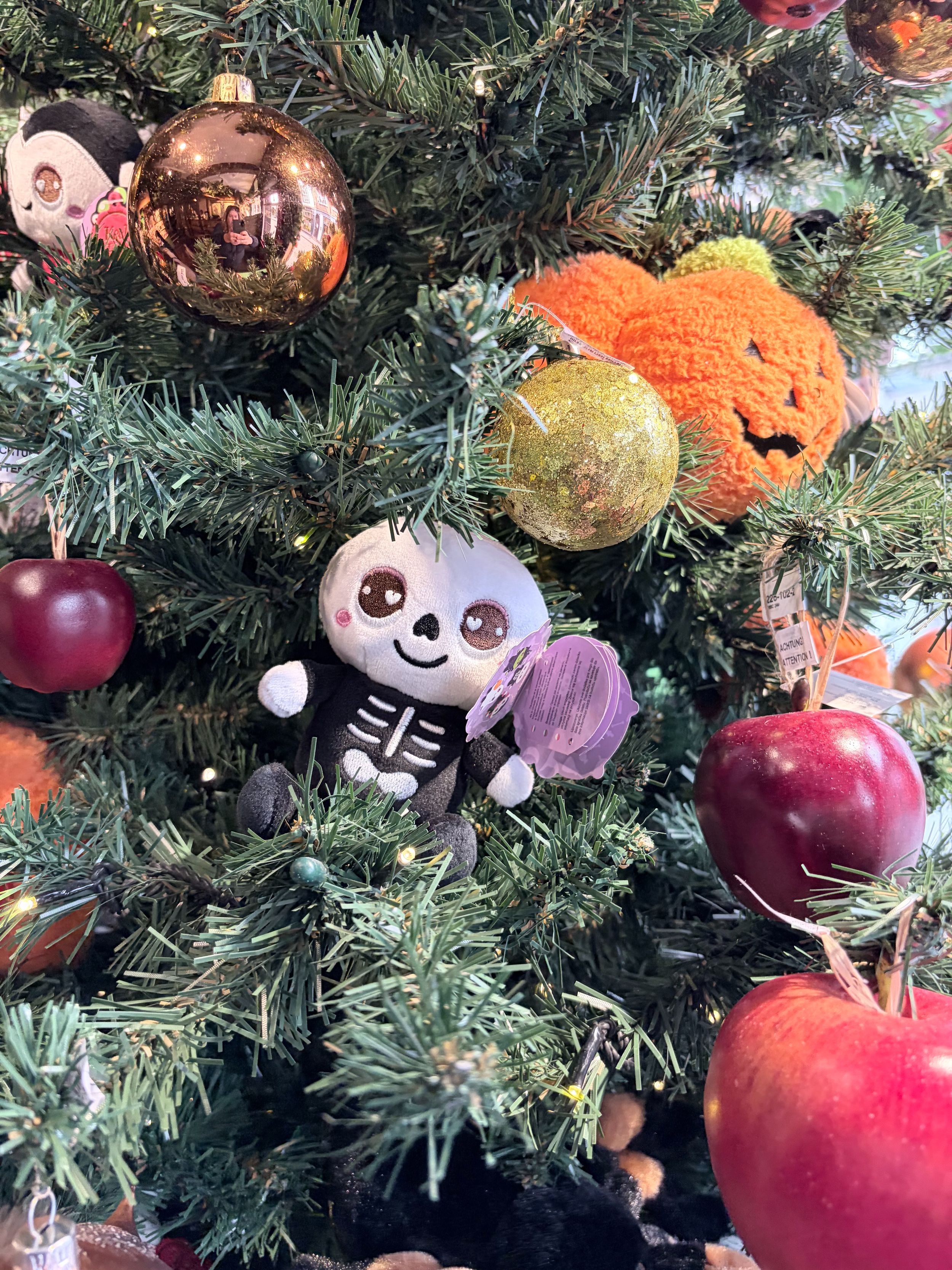 Festive tree with plush skeleton toy, apples, and pumpkin ornament