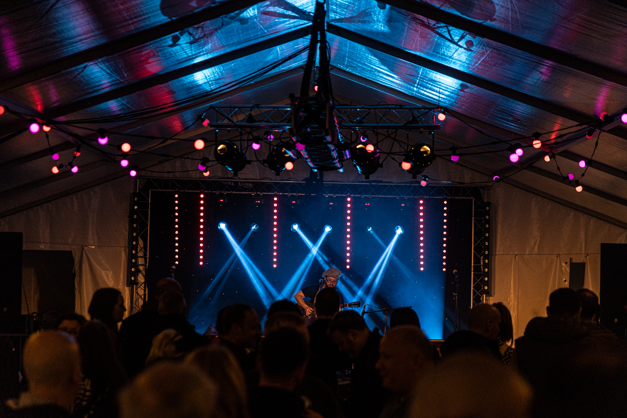 Live music performance under a tent with colourful lights