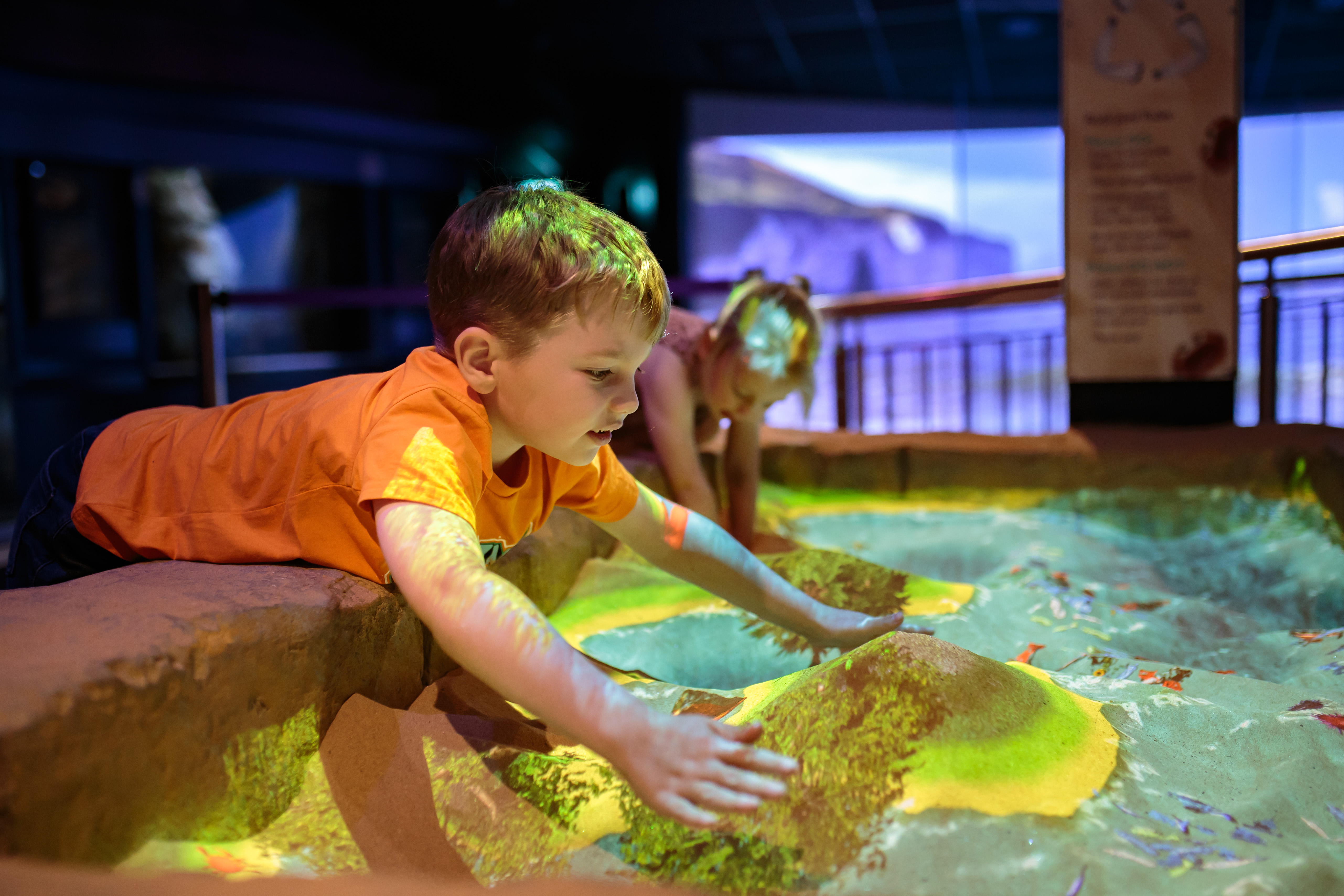 Children exploring interactive sand exhibit with colourful lights