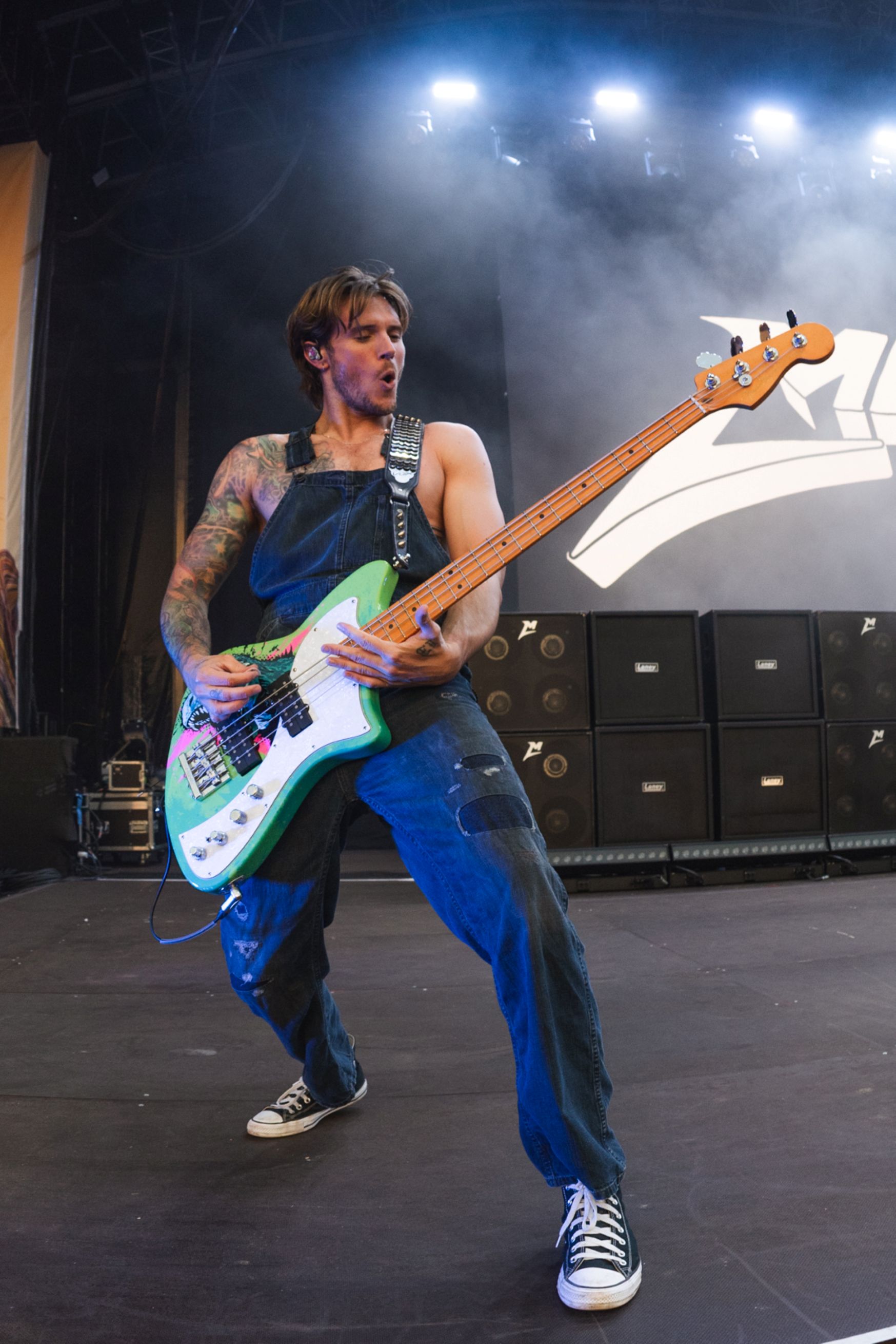 Musician in denim overalls playing electric guitar on stage