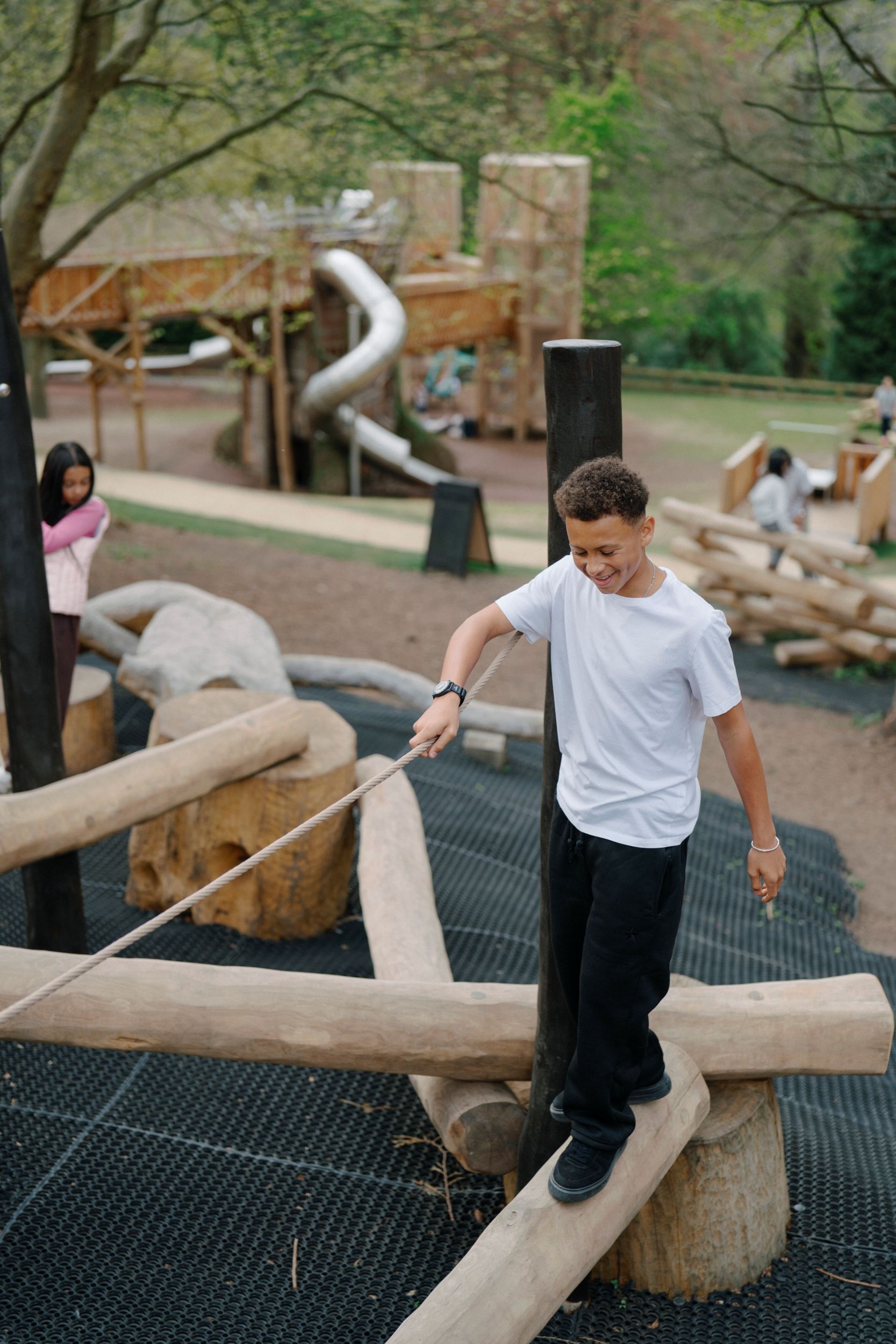 Children playing on wooden structures in a forest playground