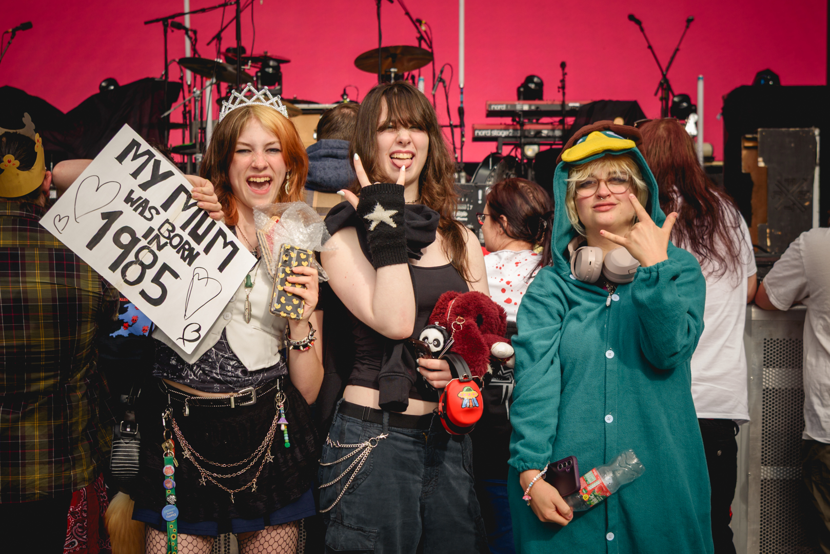 Group of young festival-goers in costumes with a sign and toys