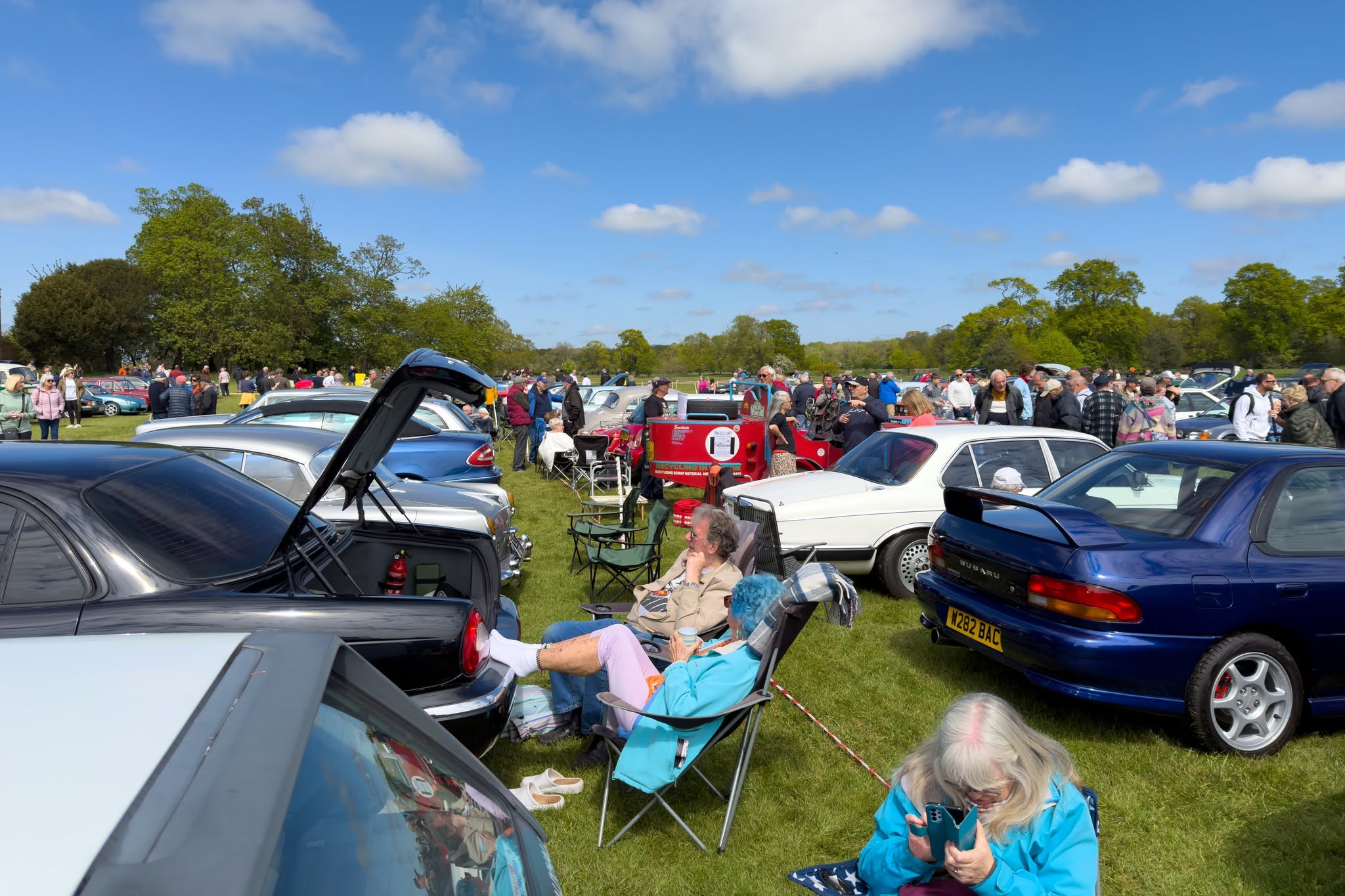 Classic car show on green field with people and vintage vehicles