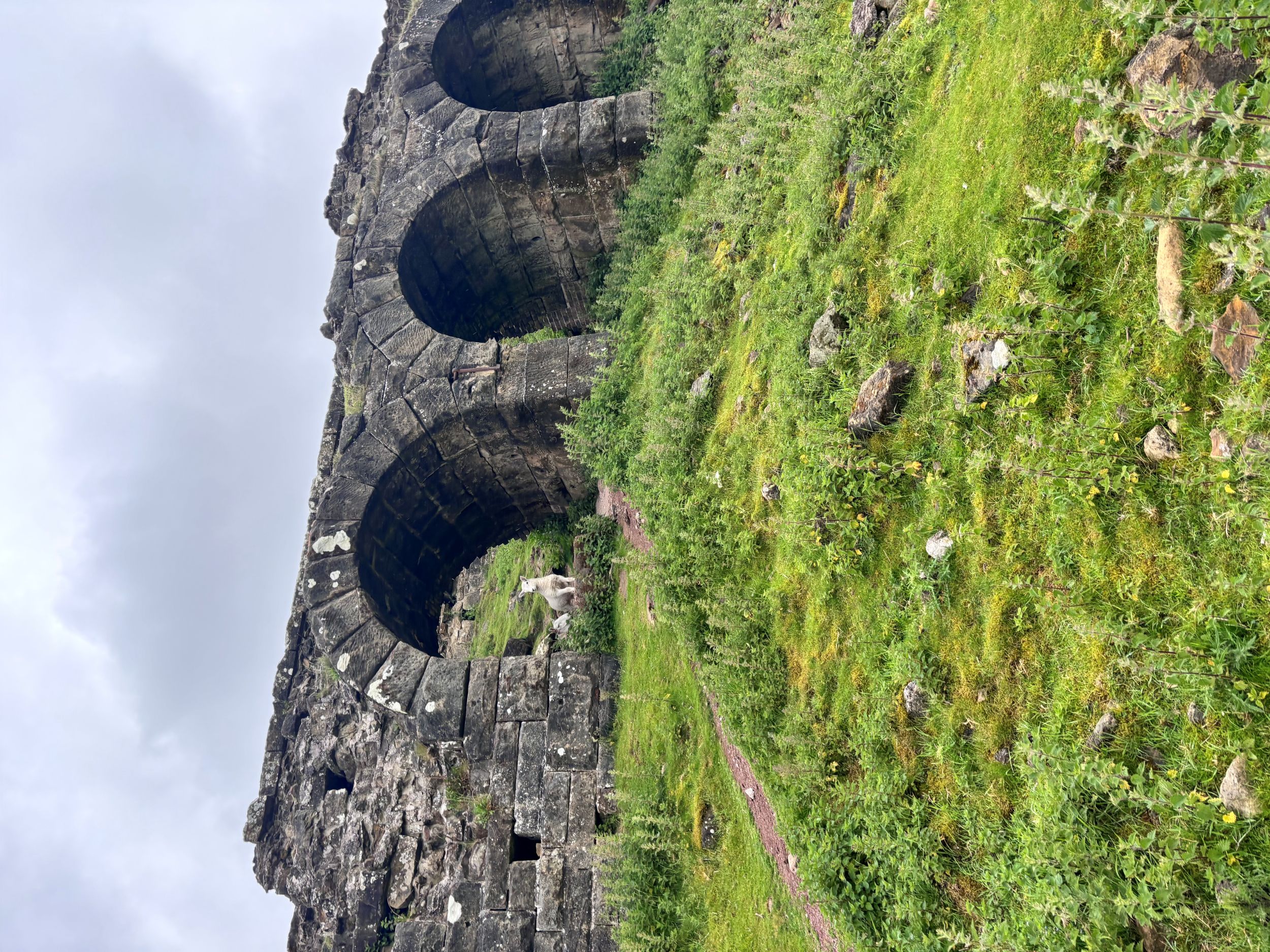 Historic stone viaduct with arches on lush green hillside