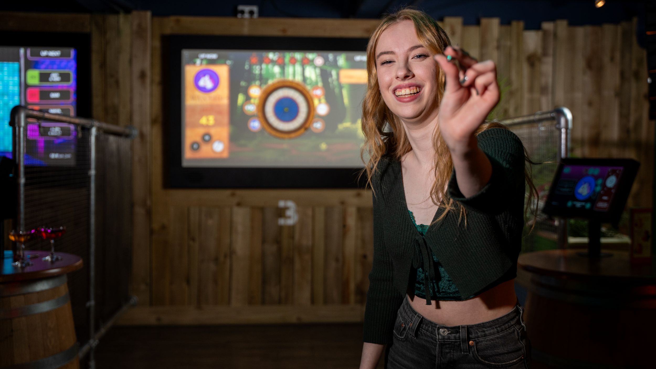 Smiling woman playing darts in indoor entertainment venue
