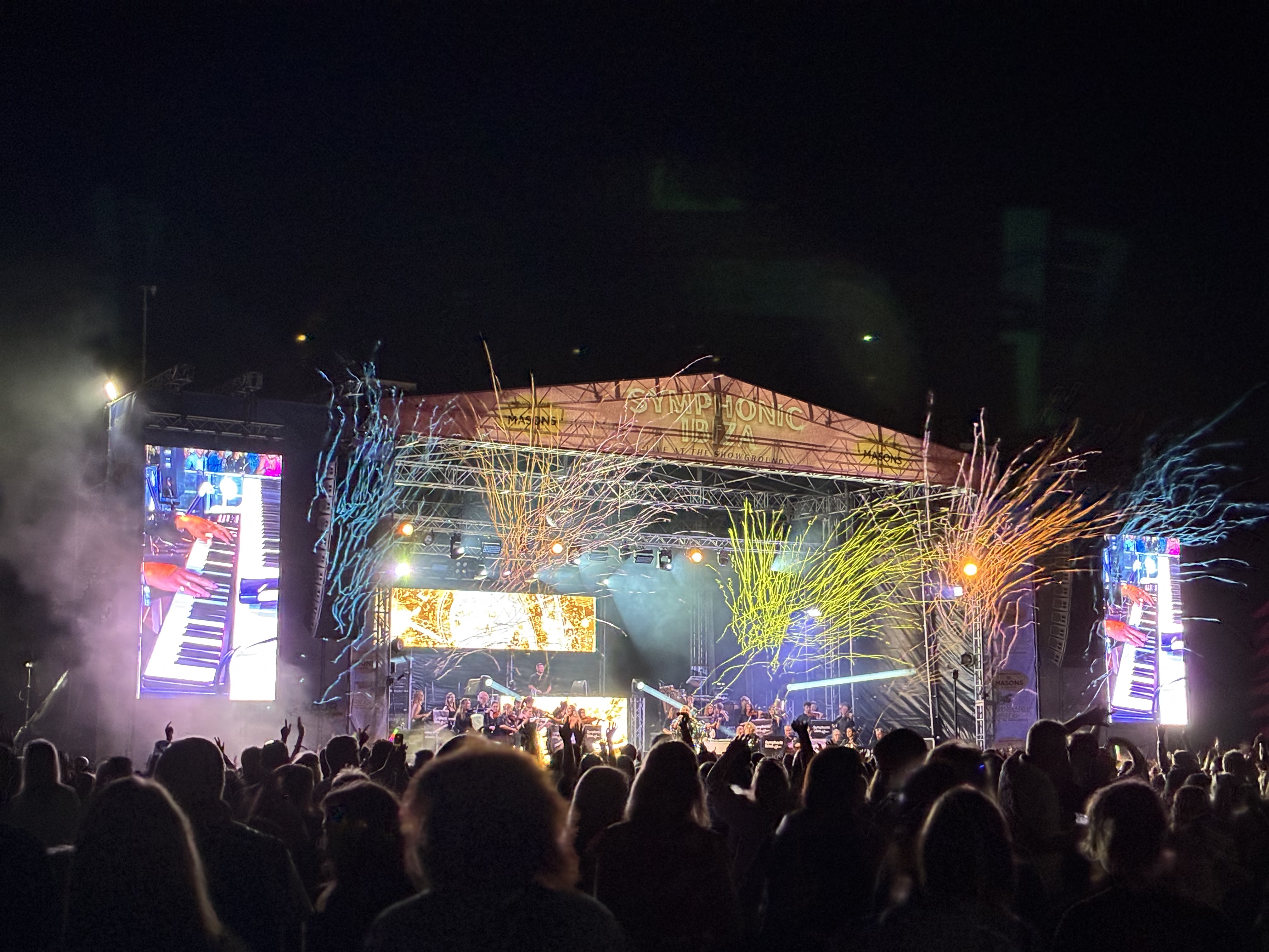 Crowd enjoying outdoor concert with colourful stage lights