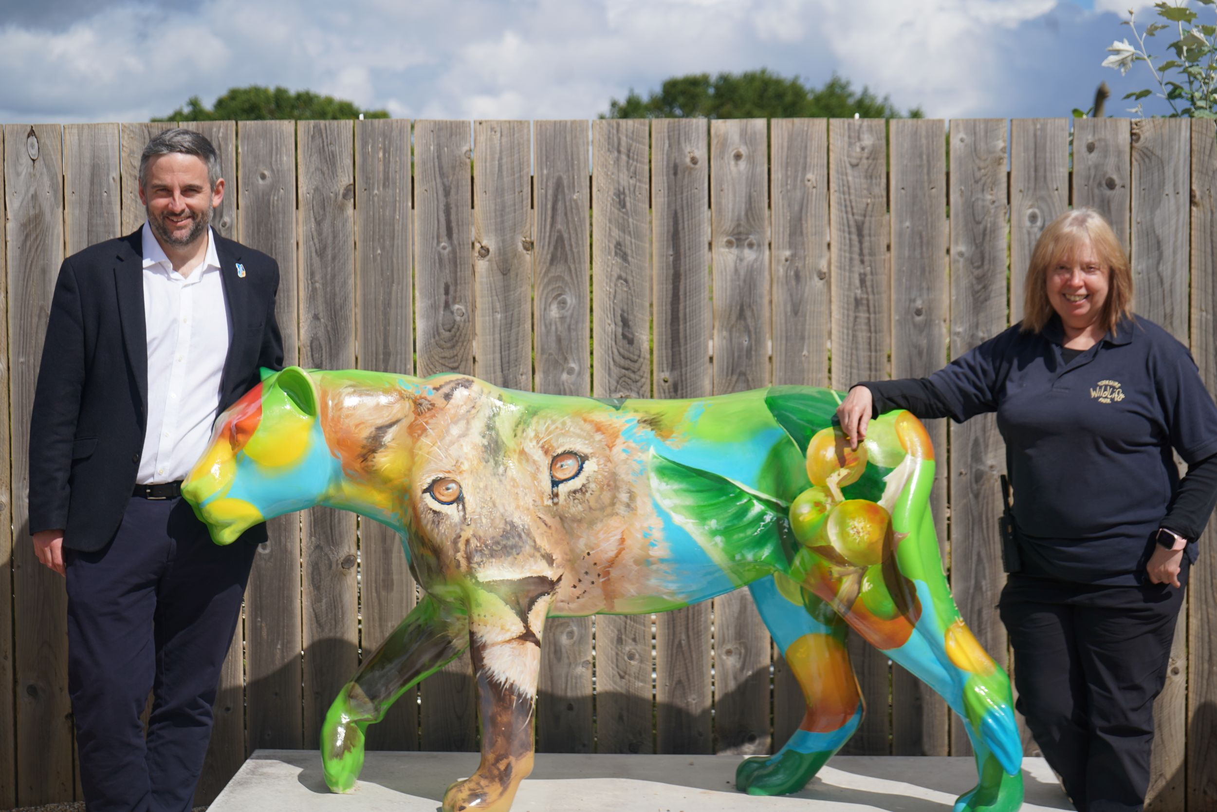 Colorful lion sculpture with two people standing beside