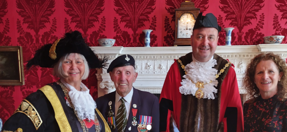 Four people in ceremonial attire in front of ornate fireplace