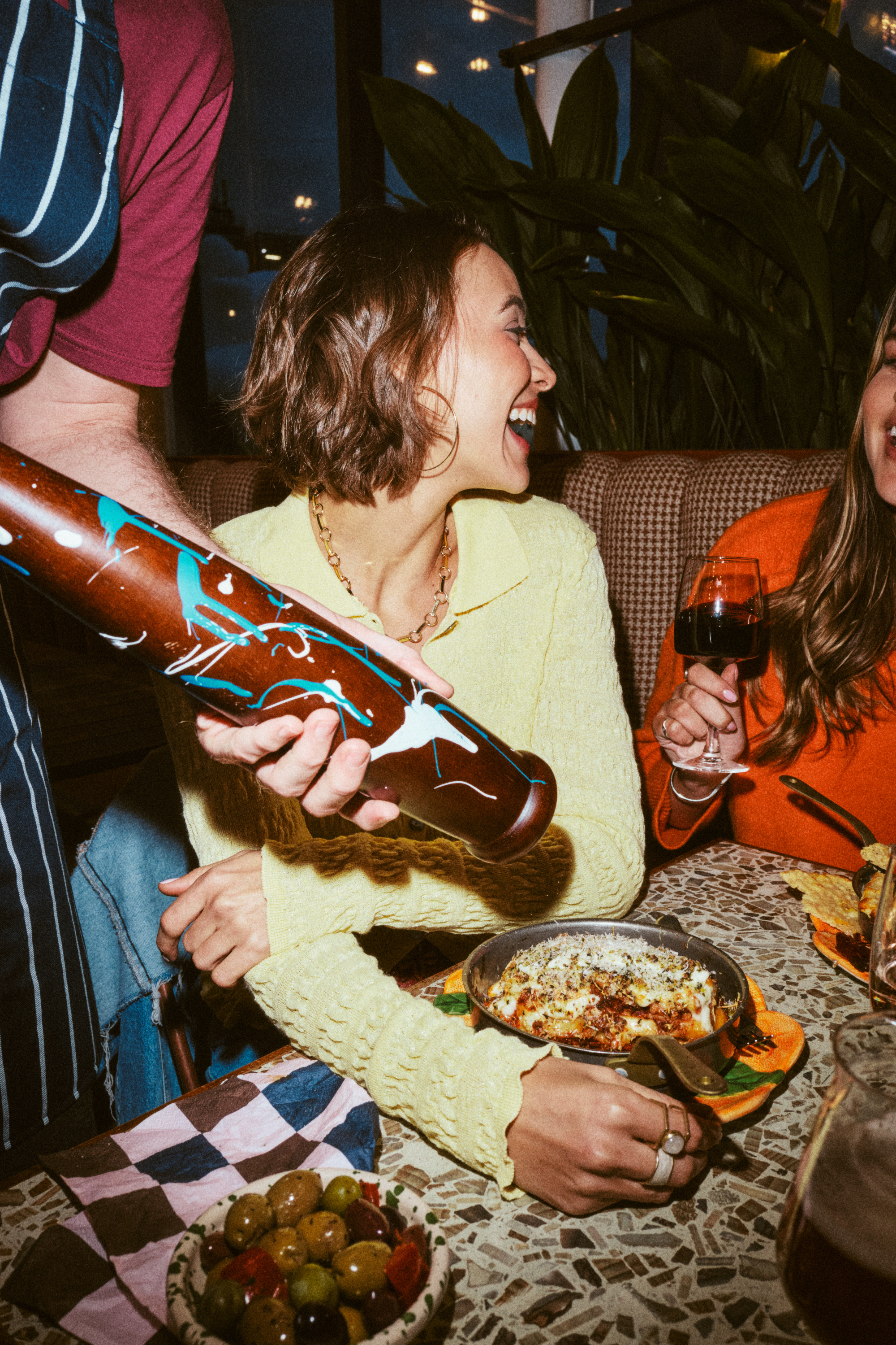 Smiling people dining indoors with wine and olives