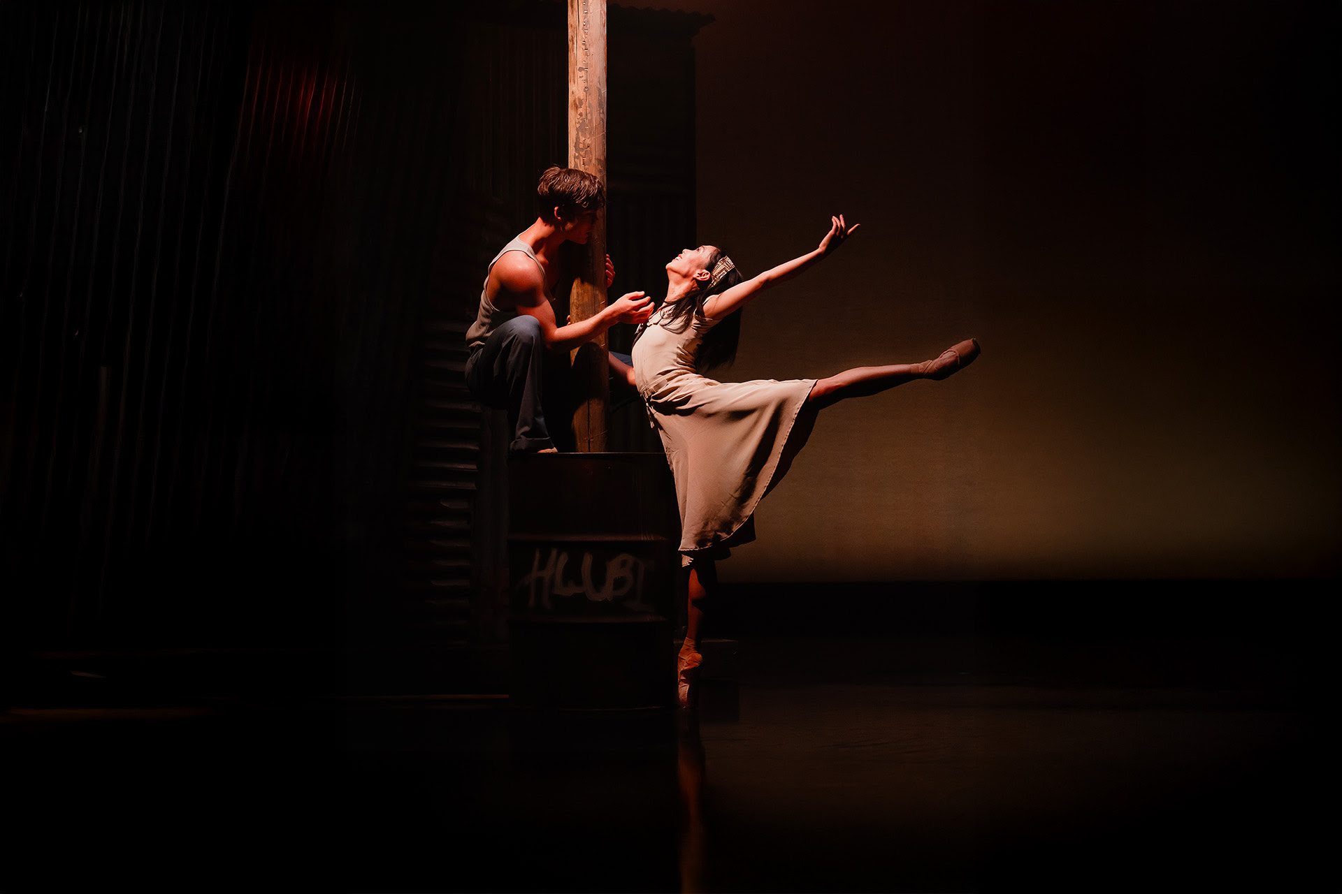 Ballet dancer performing graceful pose on dimly lit stage
