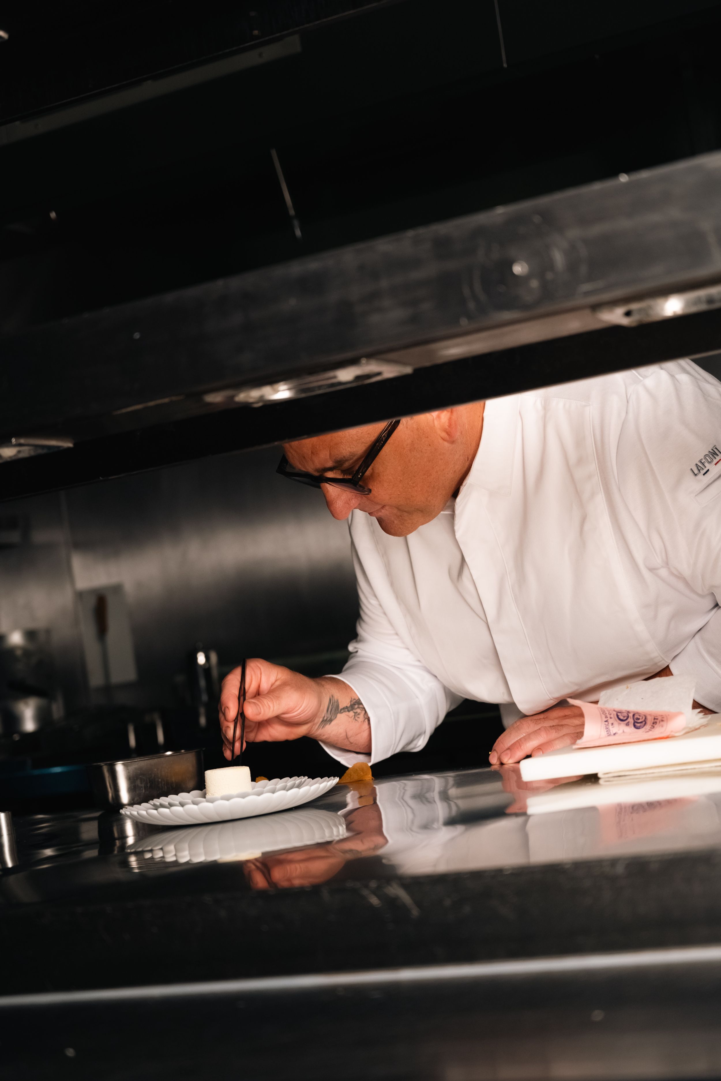 Chef in white uniform carefully plating a dessert in a kitchen
