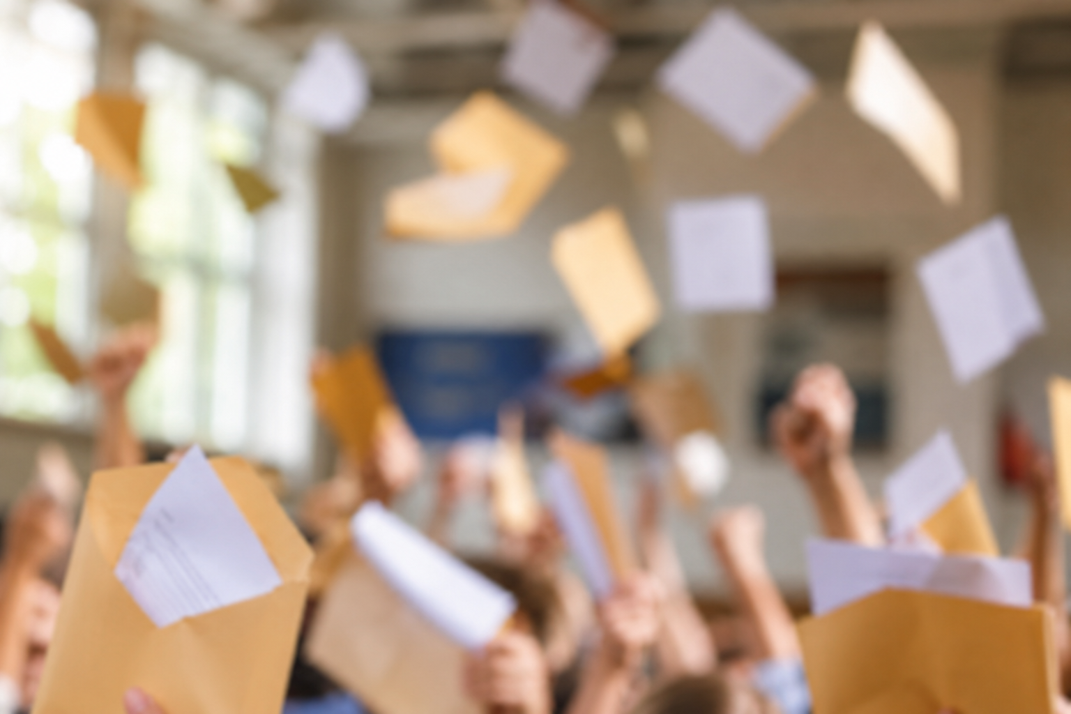 Students joyfully toss exam results envelopes in classroom