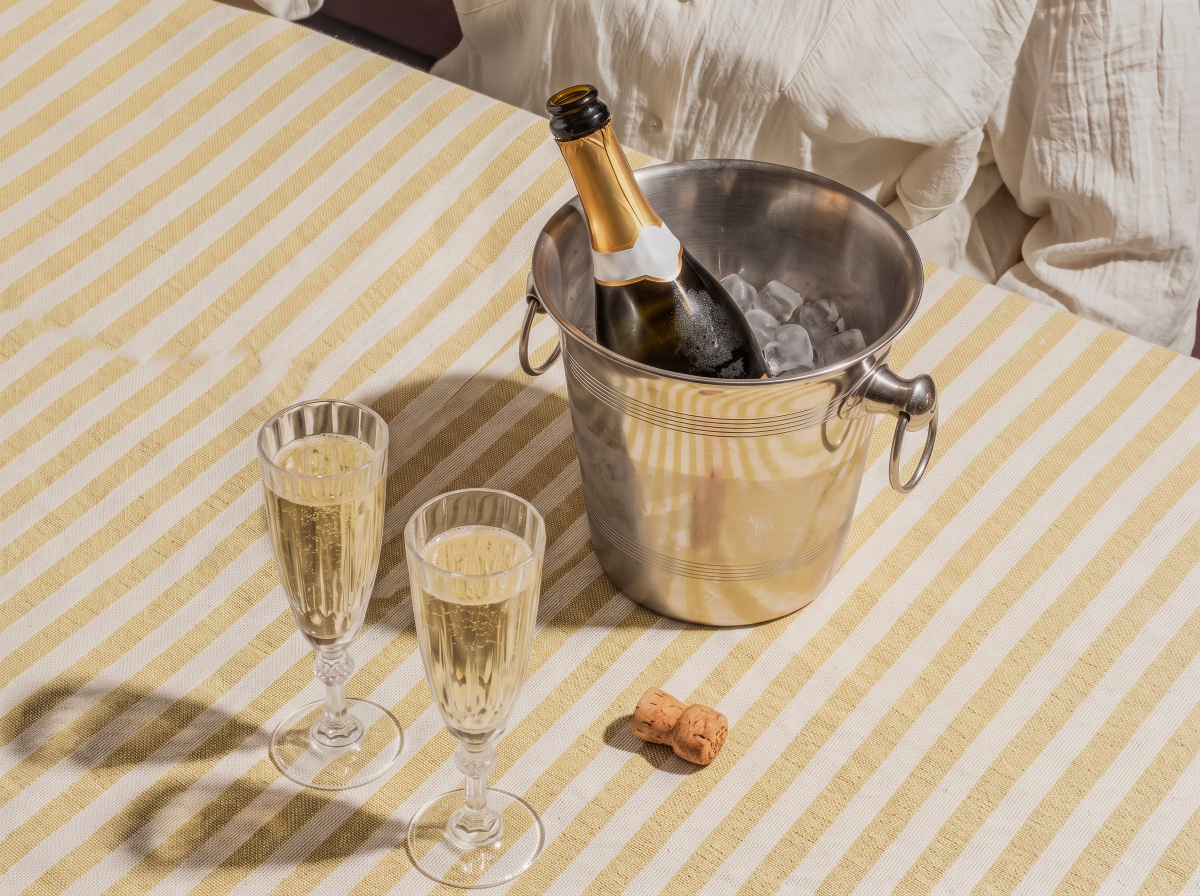Chilled champagne bottle in ice bucket with two filled glasses