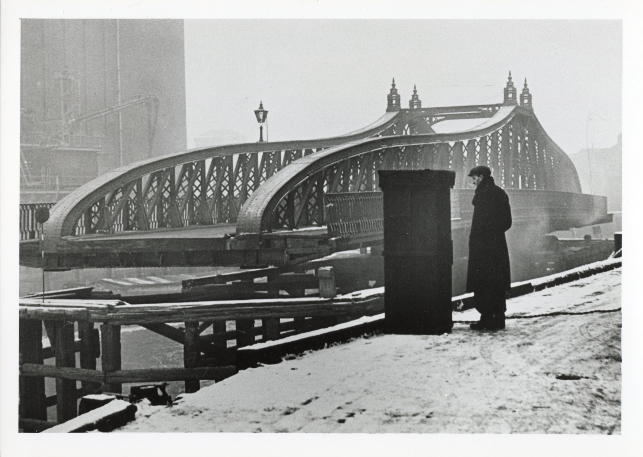 Man in coat standing near Drypool Bridge on foggy day