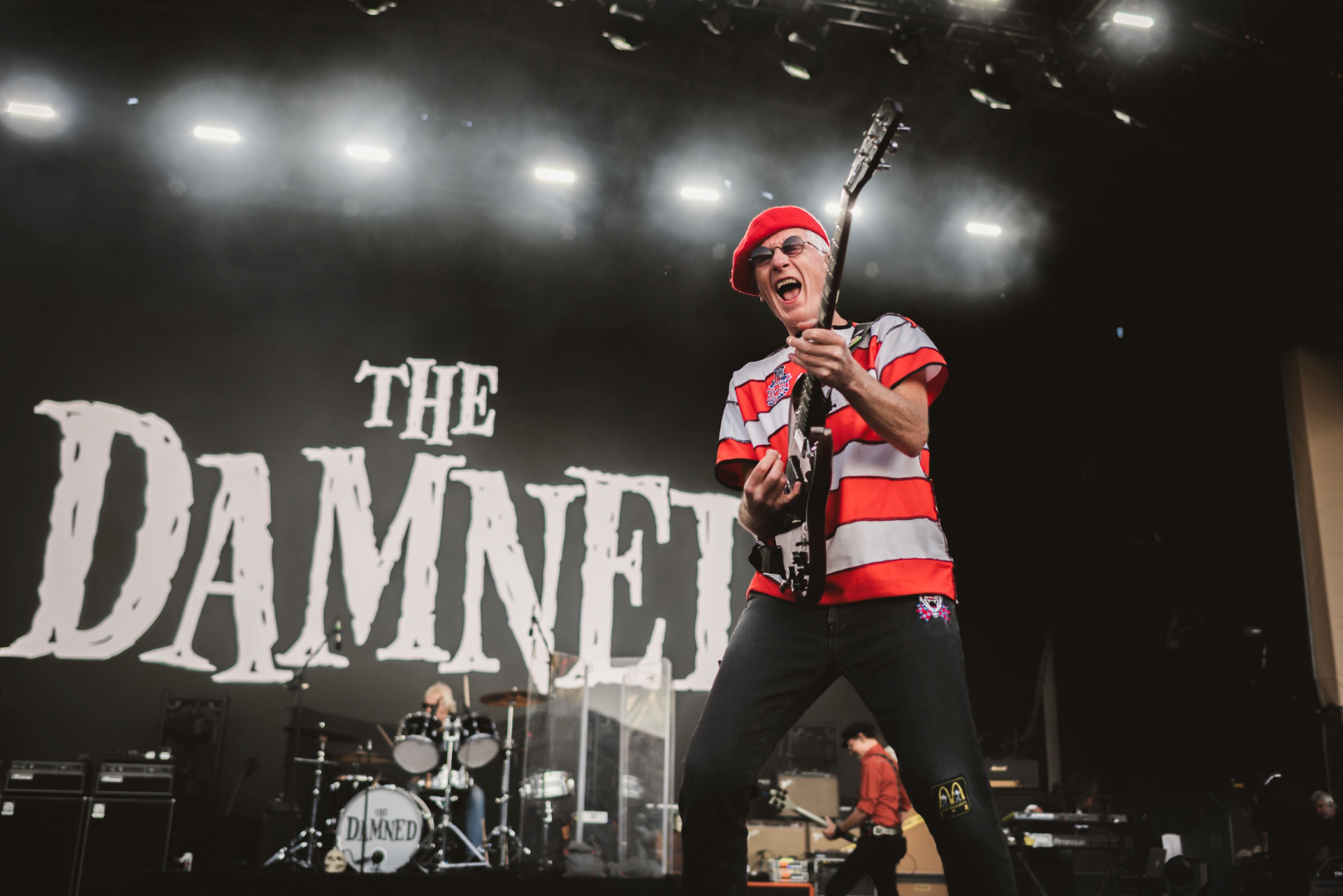 Guitarist in red beret performing energetically on stage
