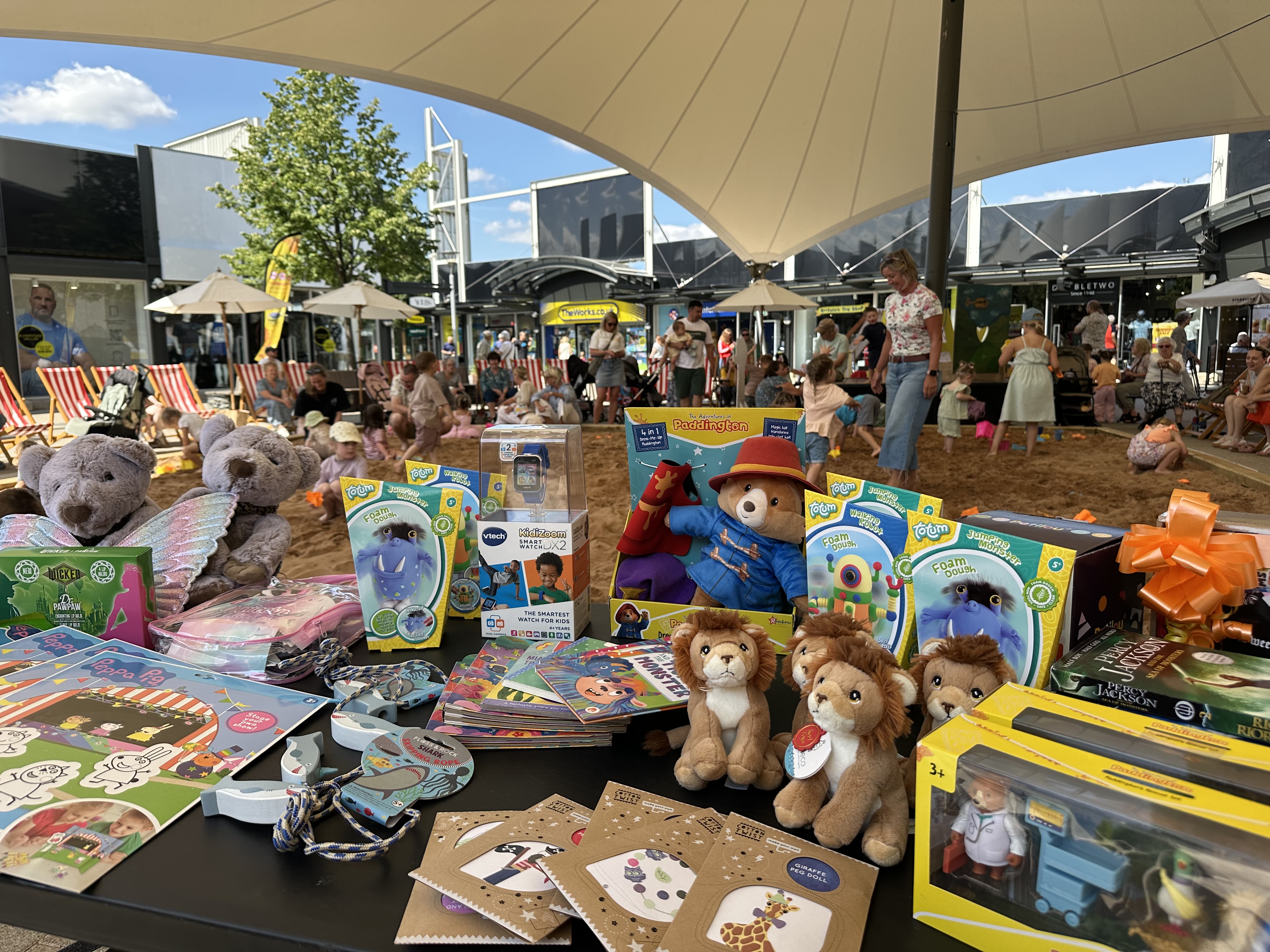 Outdoor market stall with toys, Paddington bear, and plush lions
