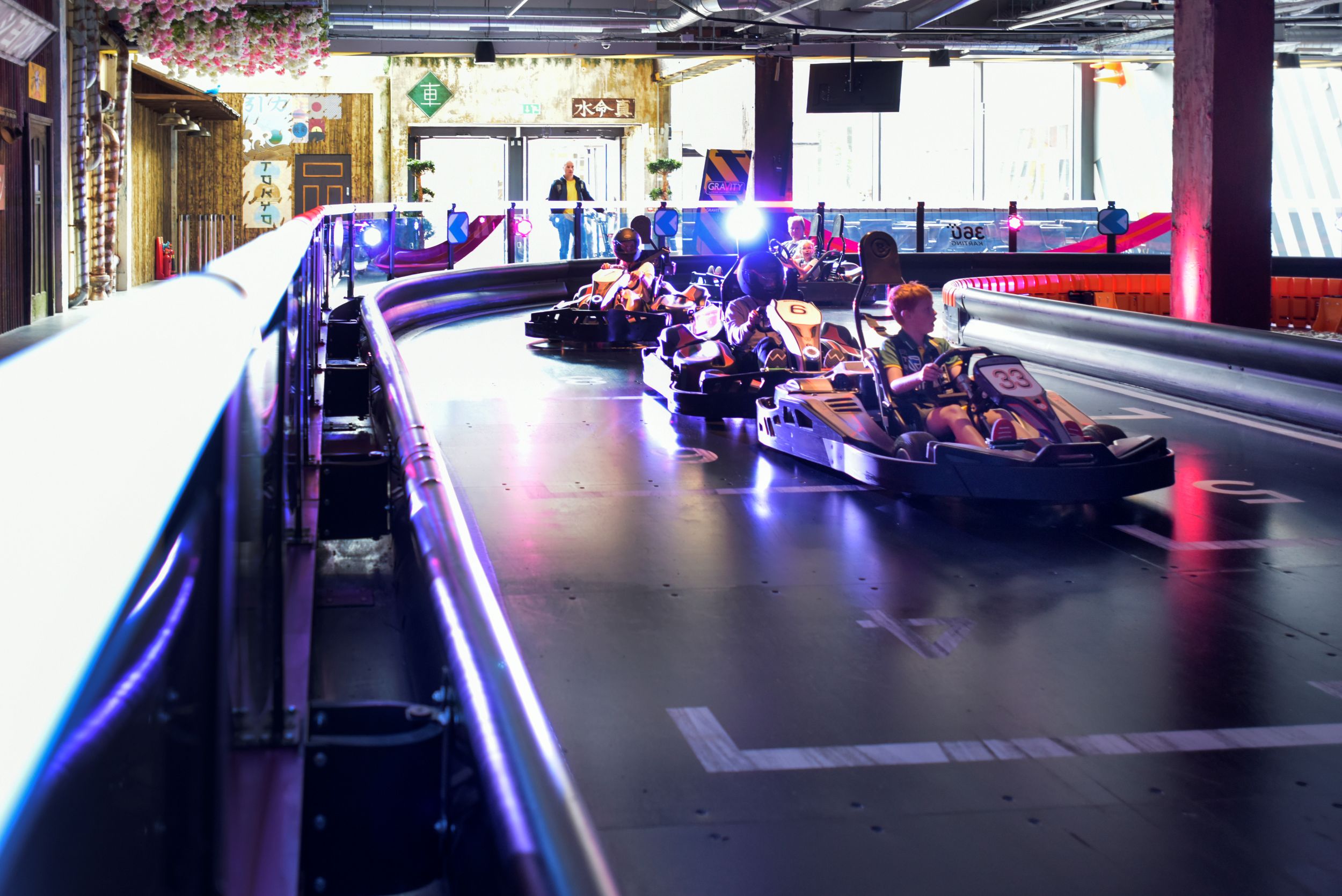 Indoor go-kart track with racers in brightly lit setting
