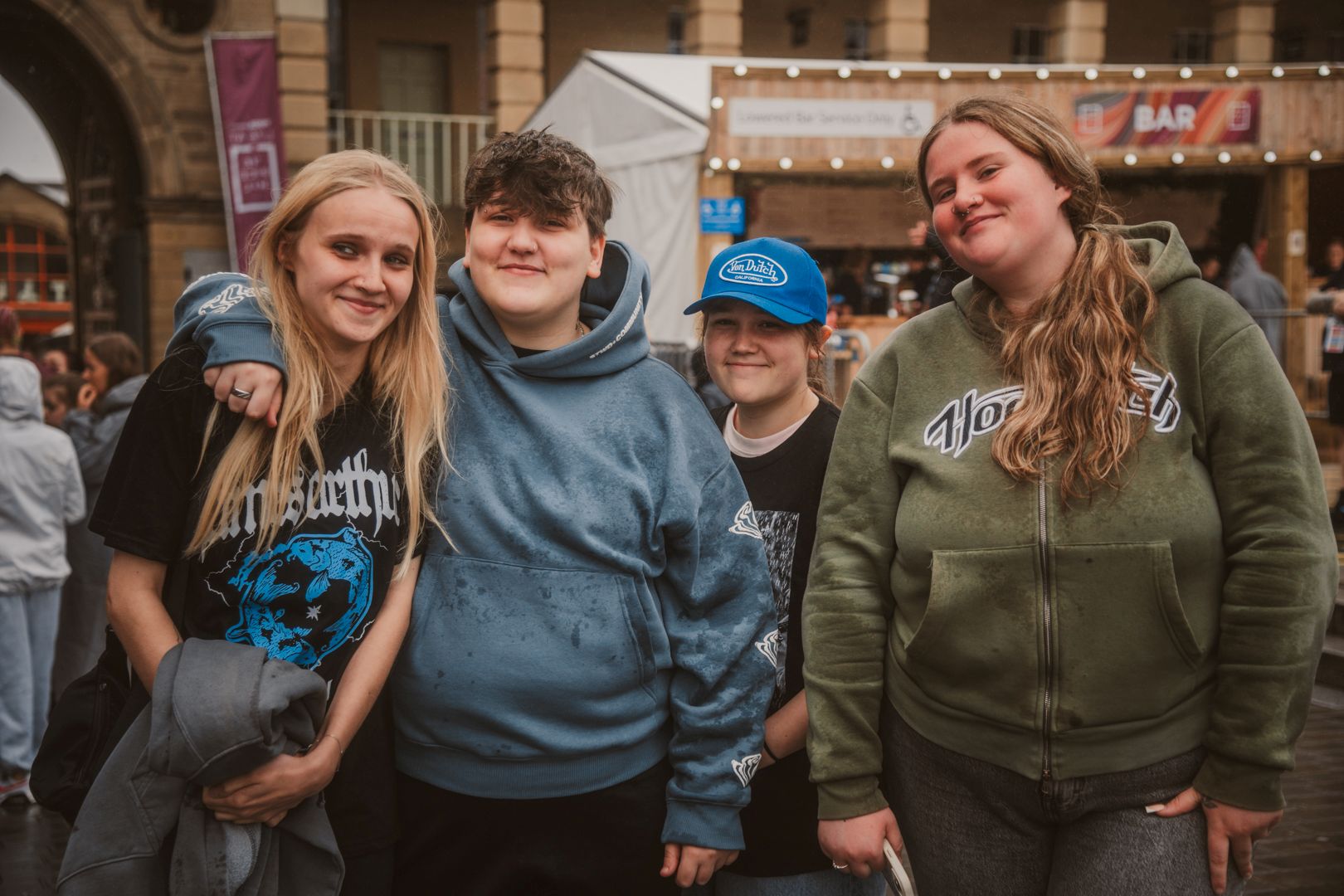 Group of four smiling friends in casual clothes at an outdoor event