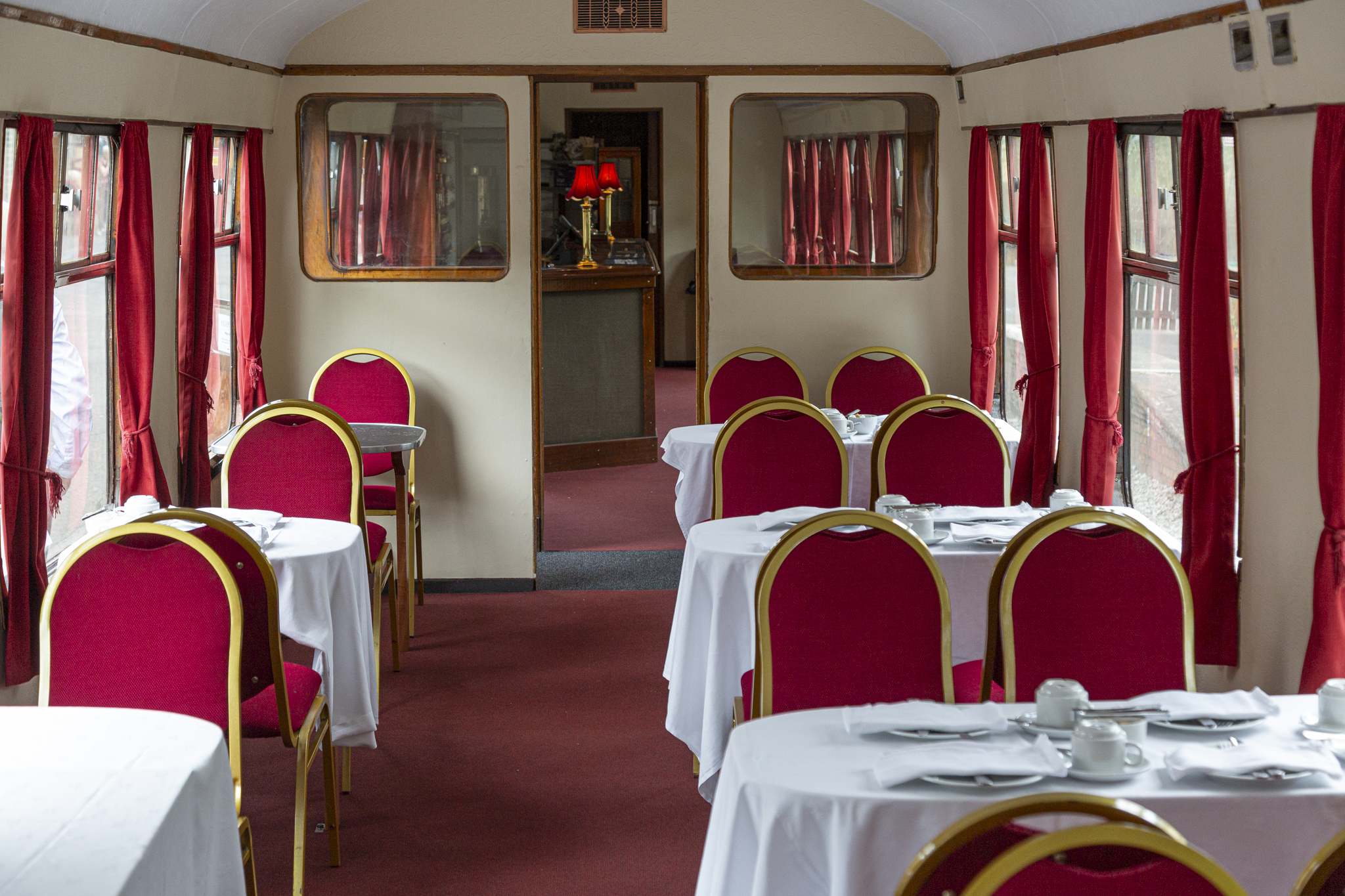 Vintage train dining car with red chairs and white tablecloths