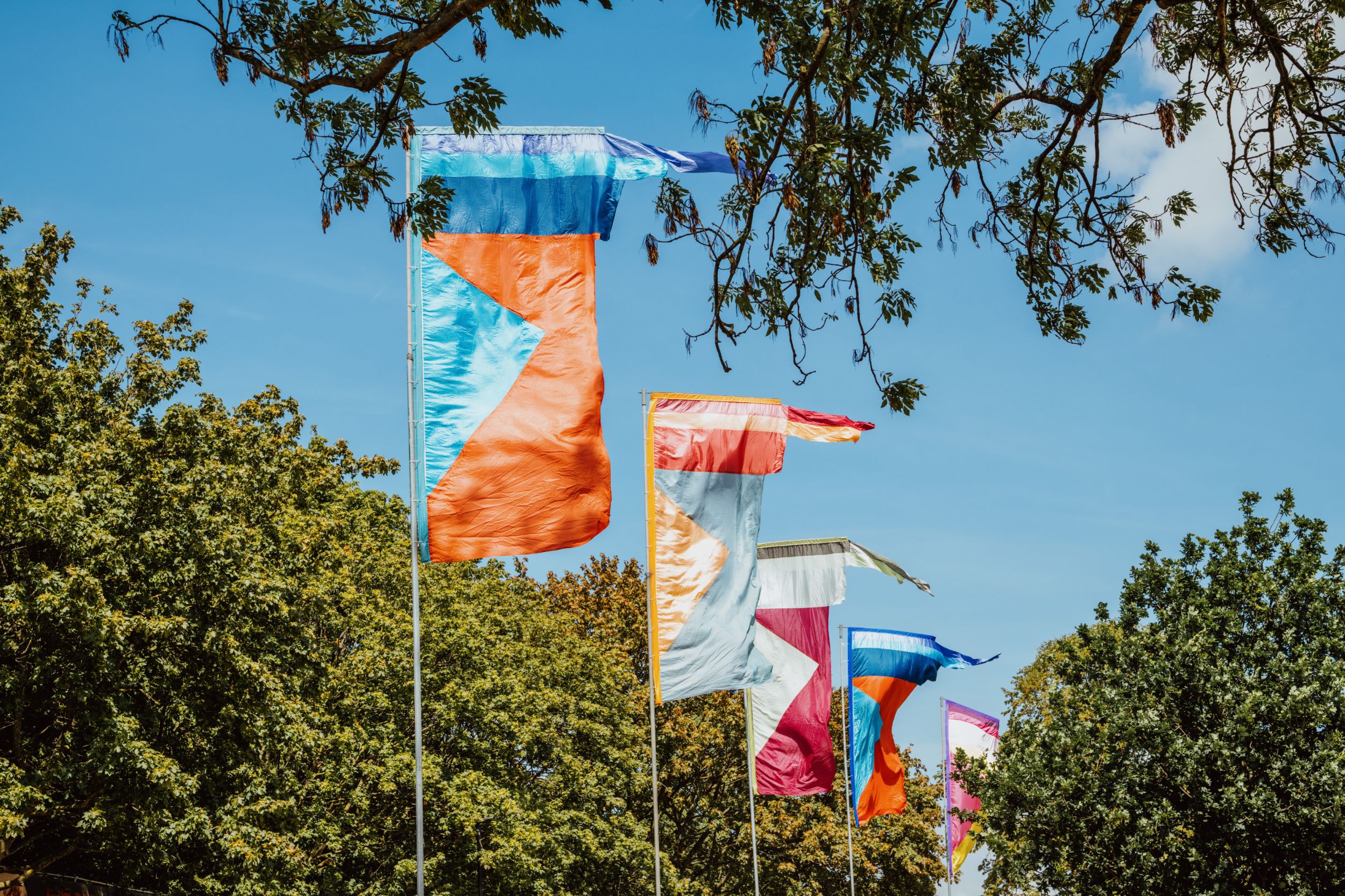 Colourful festival flags fluttering among green trees