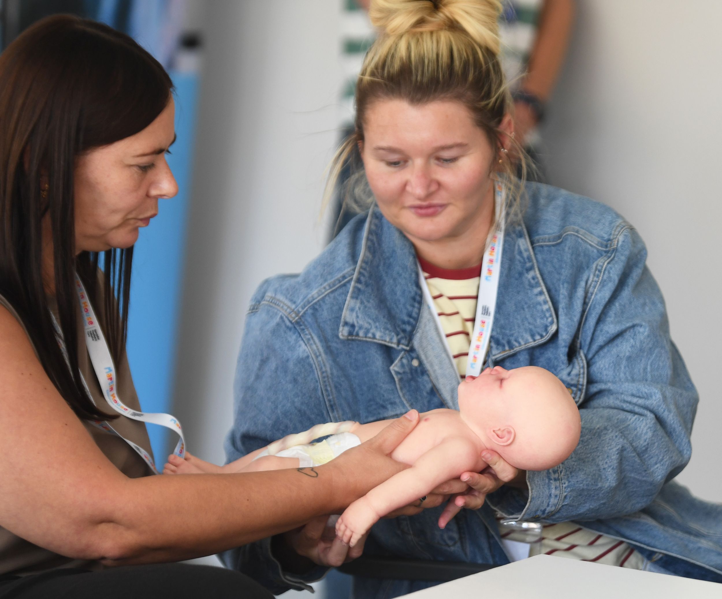 Two women practising infant CPR on a baby mannequin