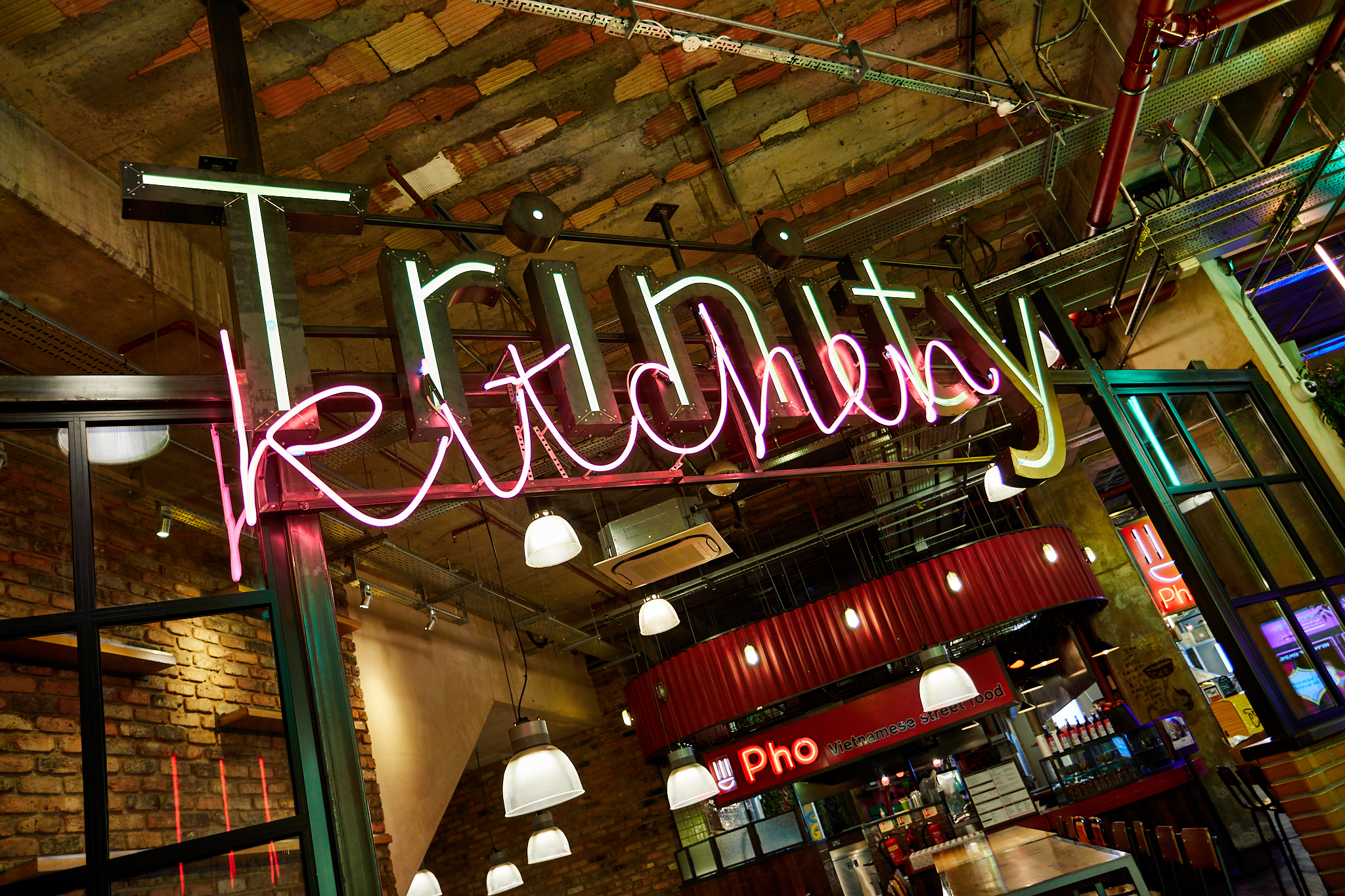 Neon sign of Trinity Kitchen in industrial setting