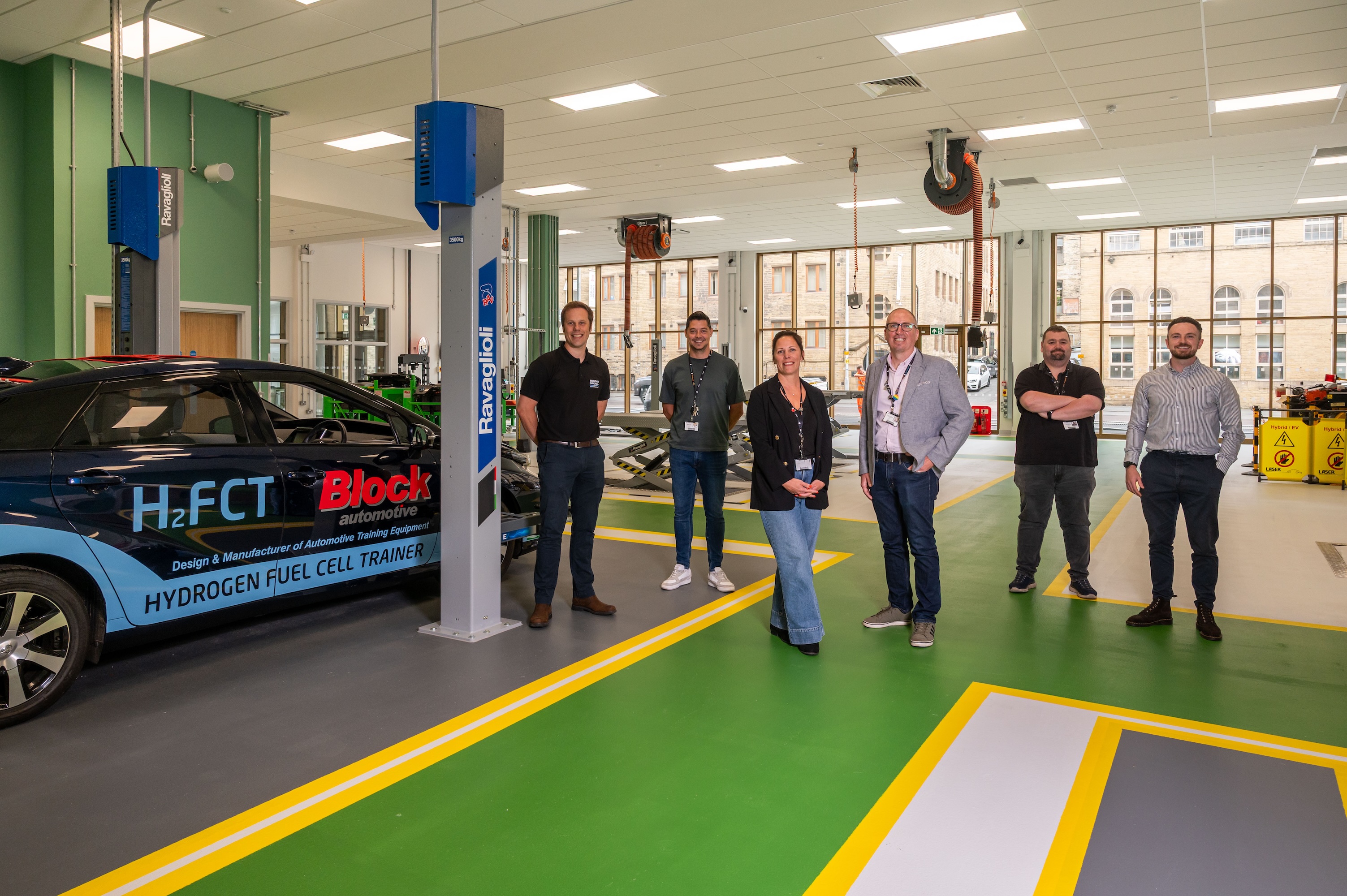 Group of people in a modern automotive workshop with equipment