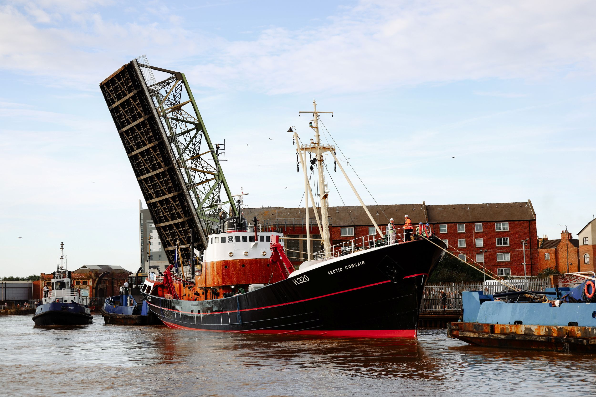 Large fishing trawler passing beneath raised swing bridge