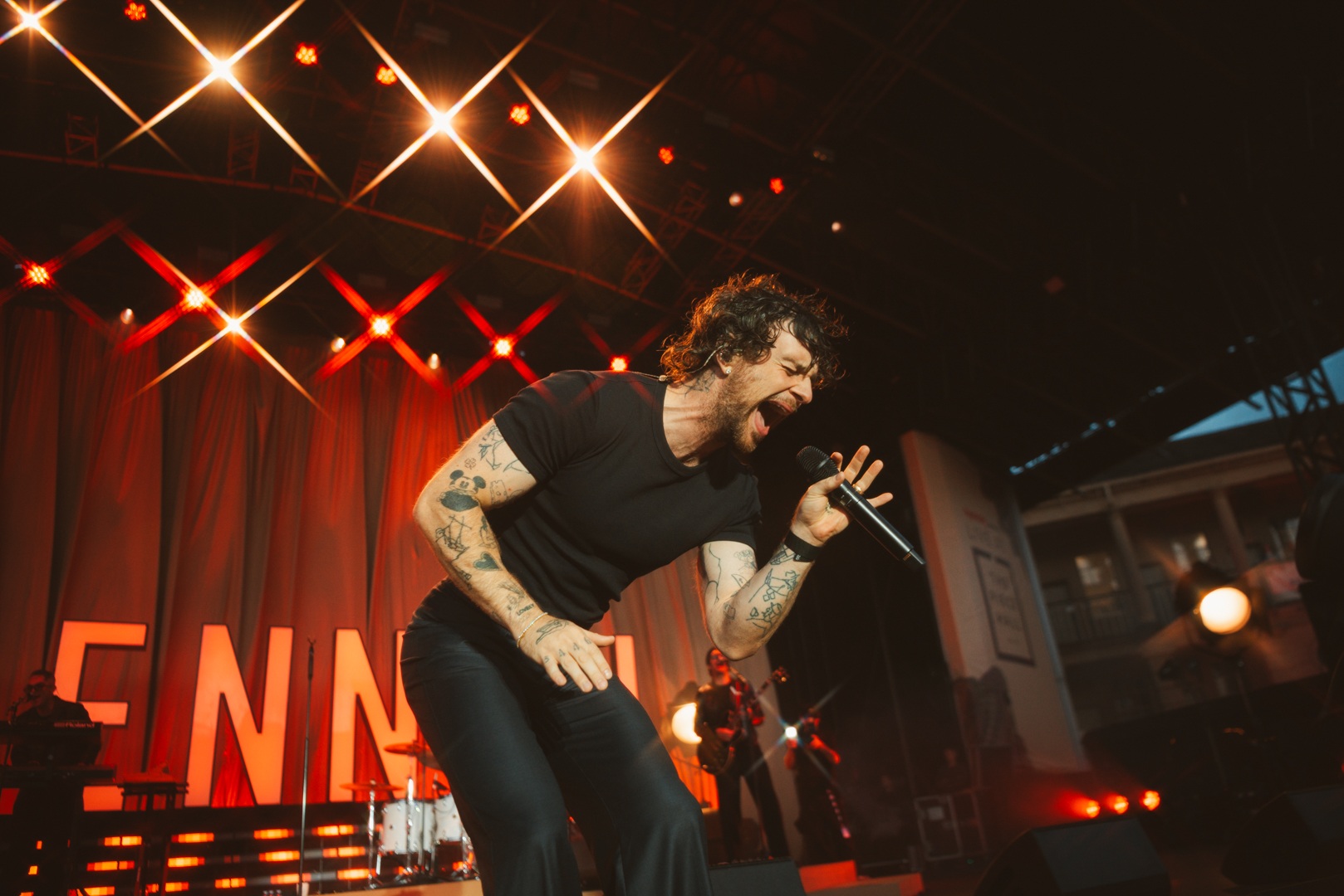 Energetic singer performing on stage with bright lights and band