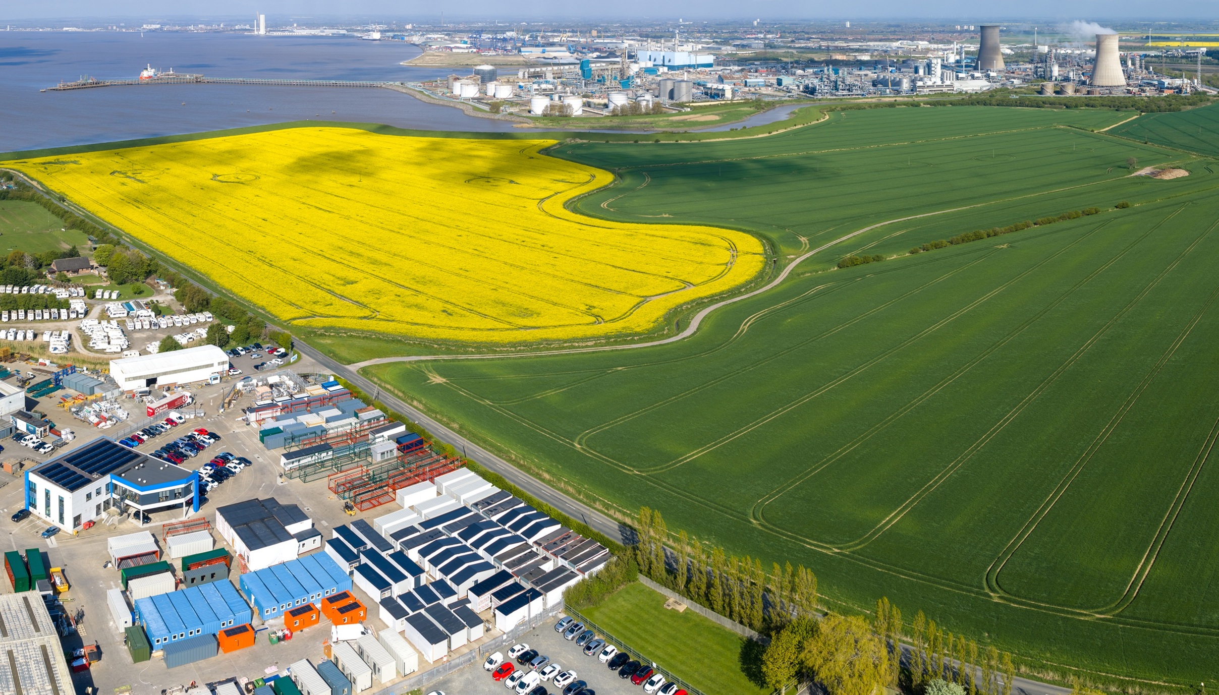 Aerial view of bright yellow rapeseed field near industrial area