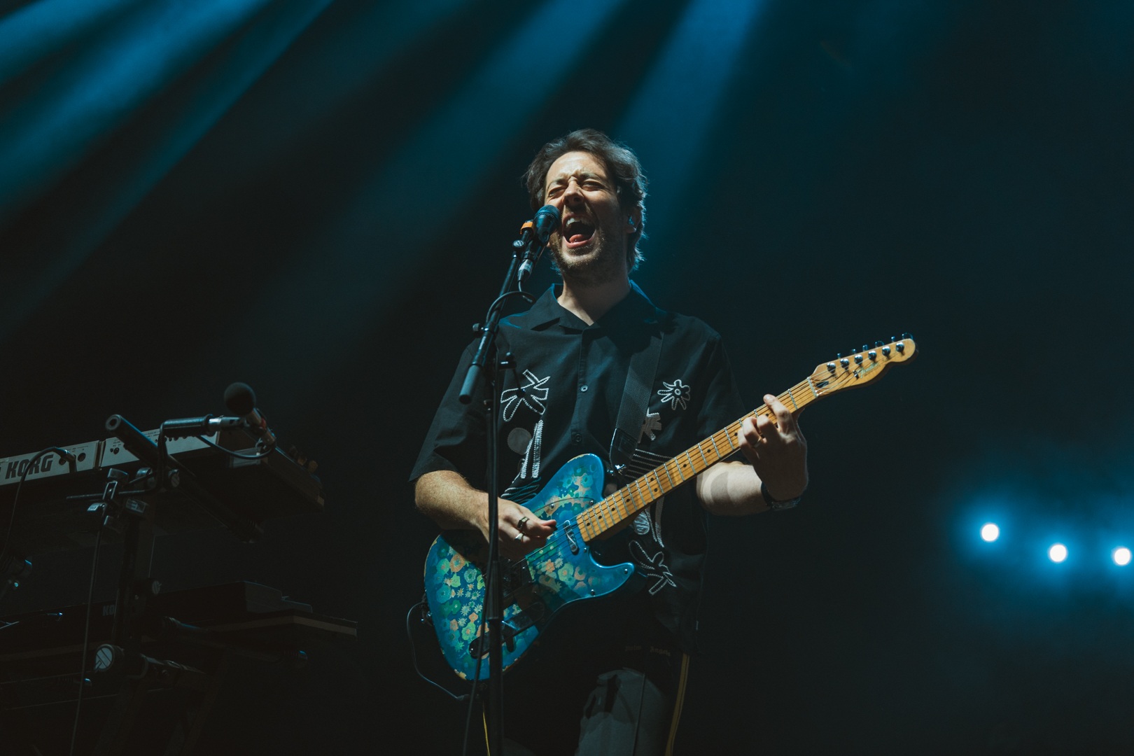 Musician playing electric guitar on stage under blue lighting