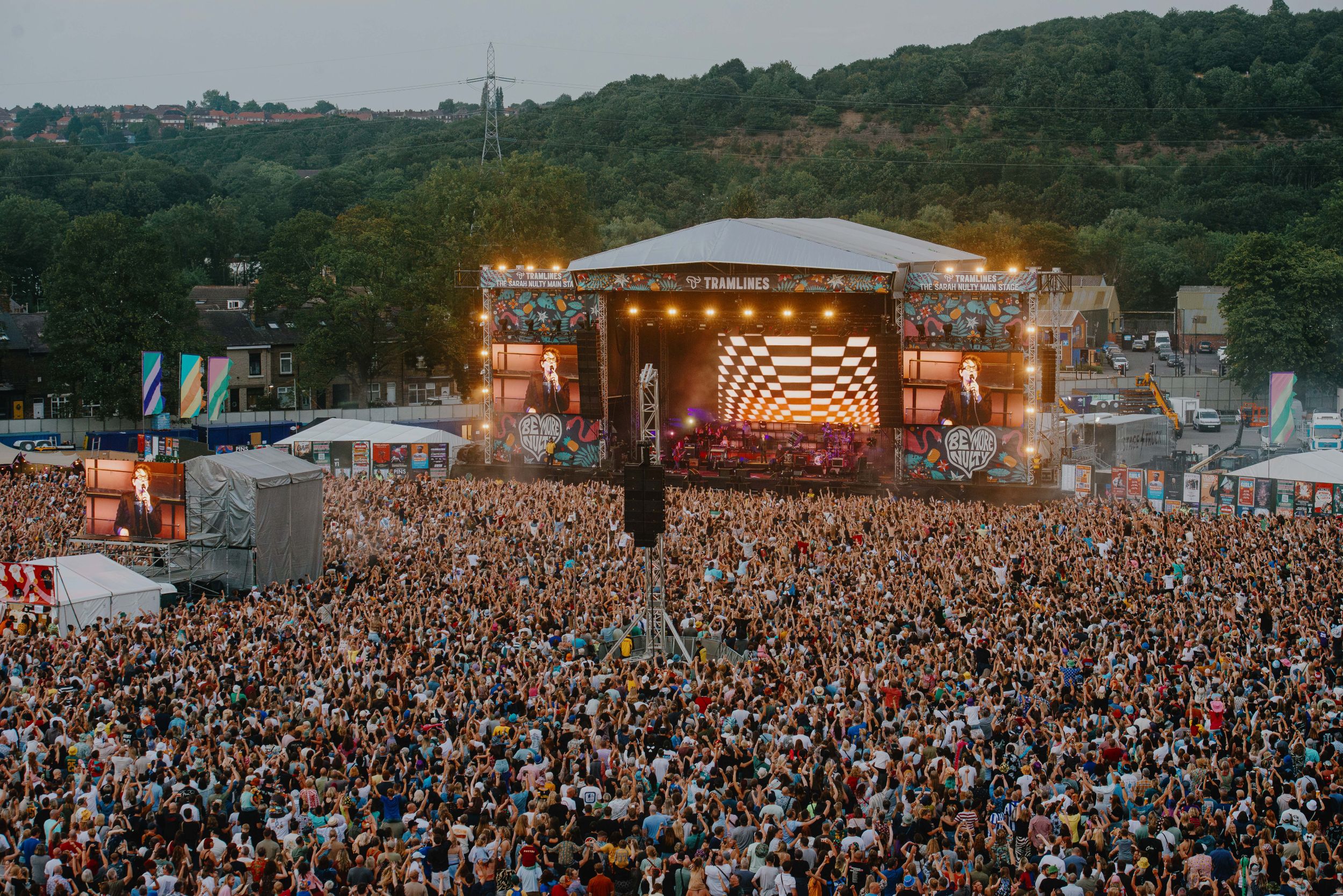 Crowd enjoying live music at outdoor festival with lit stage