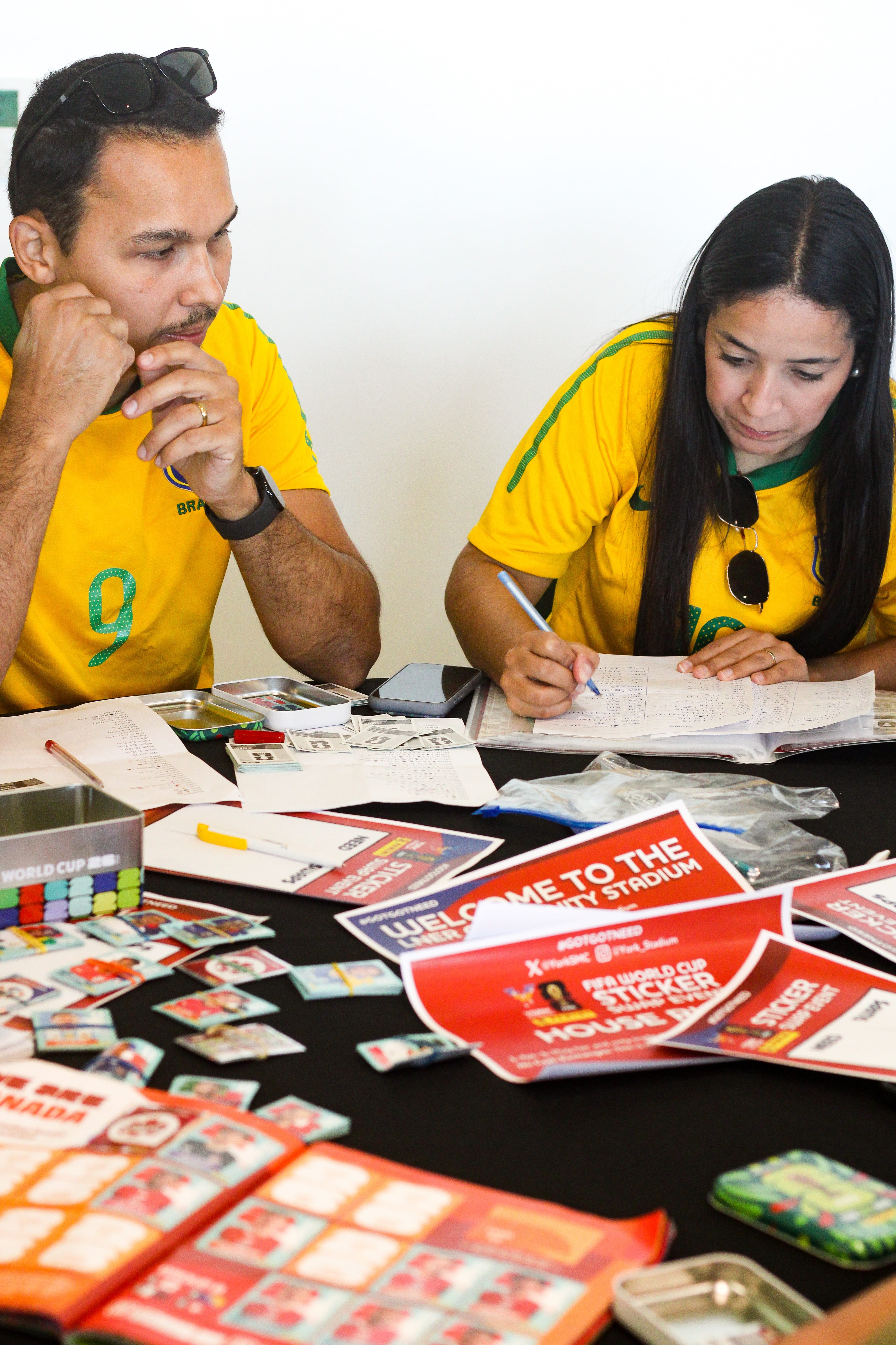 Two people in yellow jerseys writing at a table with papers
