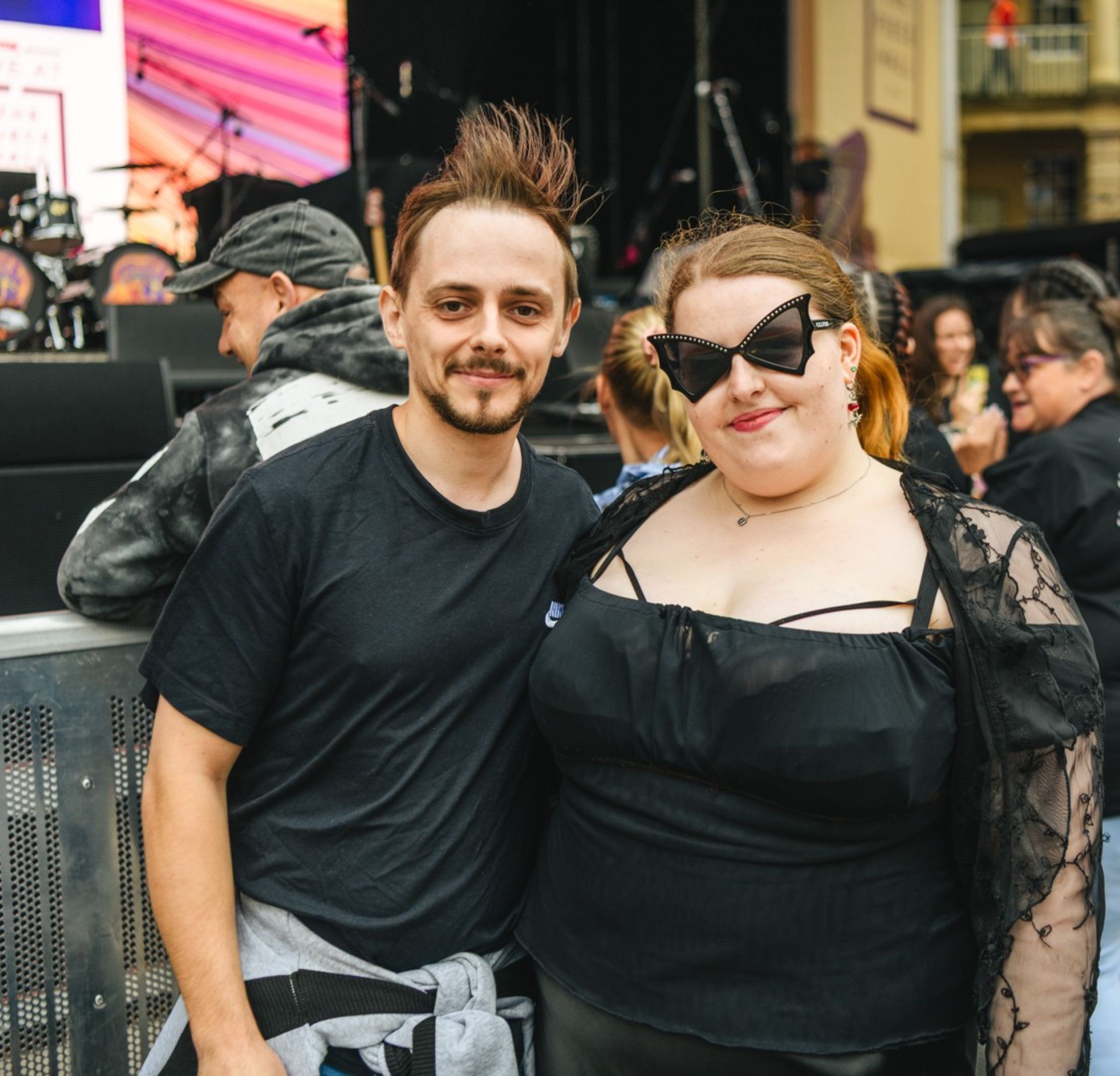 Smiling man and woman in stylish outfits at outdoor festival