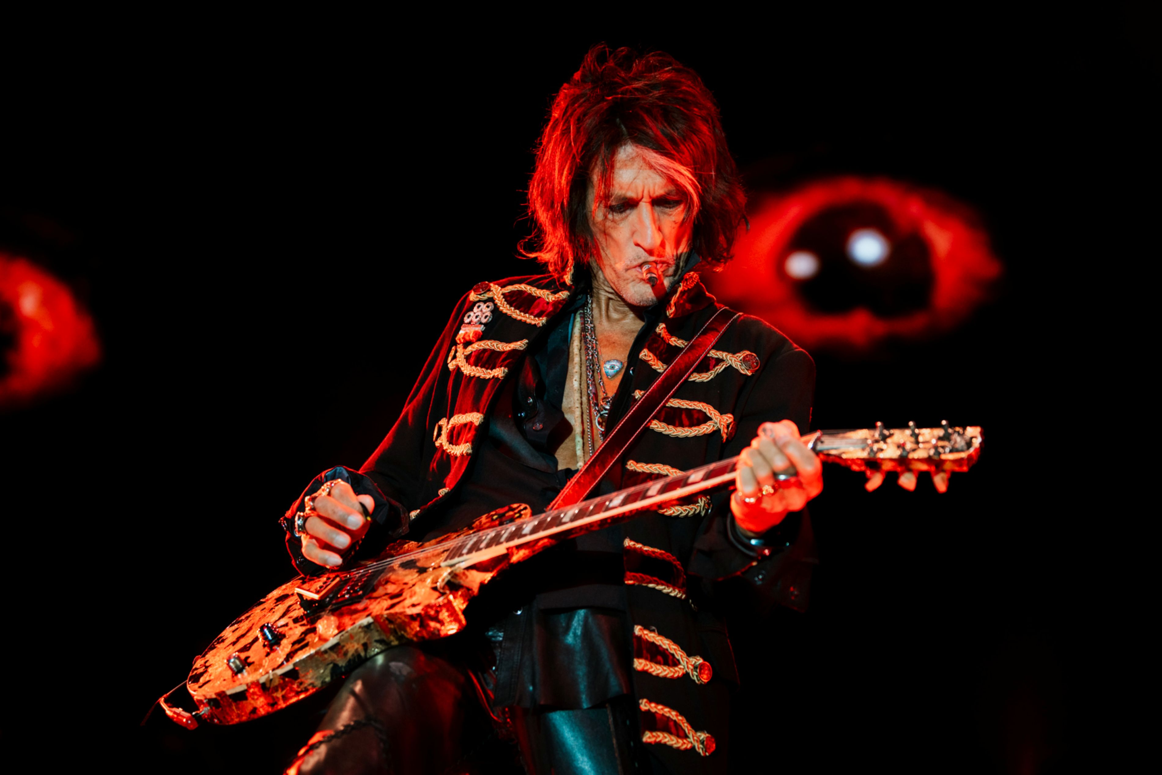 Guitarist in elaborate jacket performing on stage at night