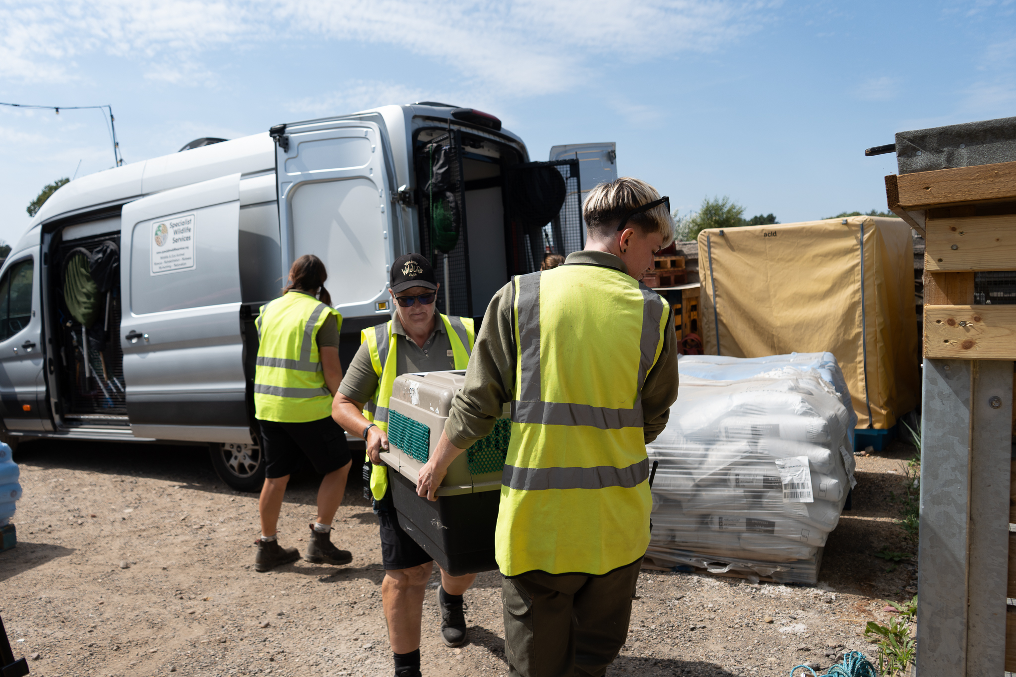 Volunteers in high-vis vests unloading supplies from a van