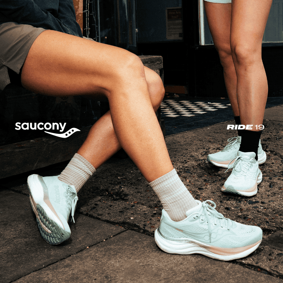 Two people wearing light blue running shoes on city pavement