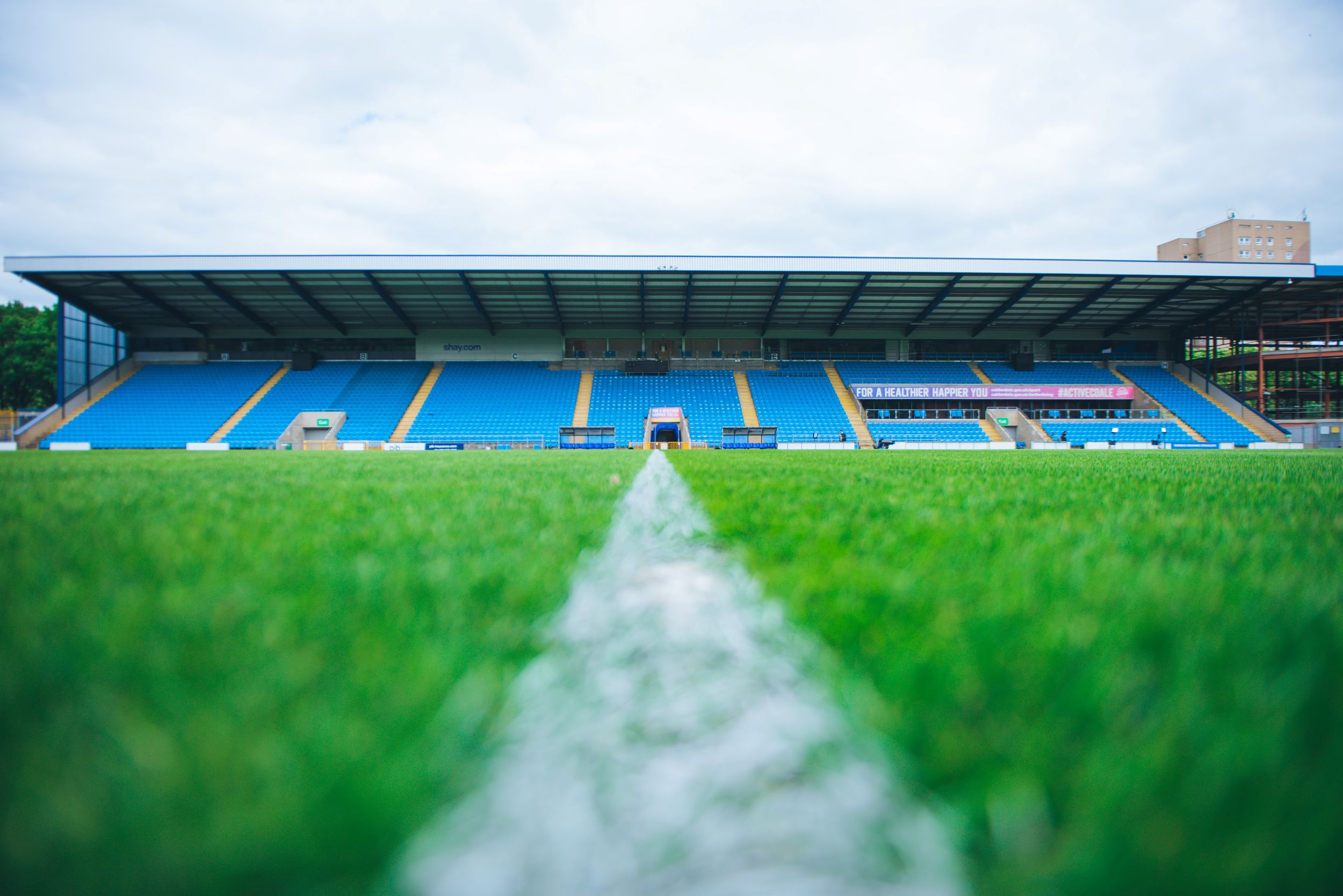 Football stadium with blue seats and green pitch