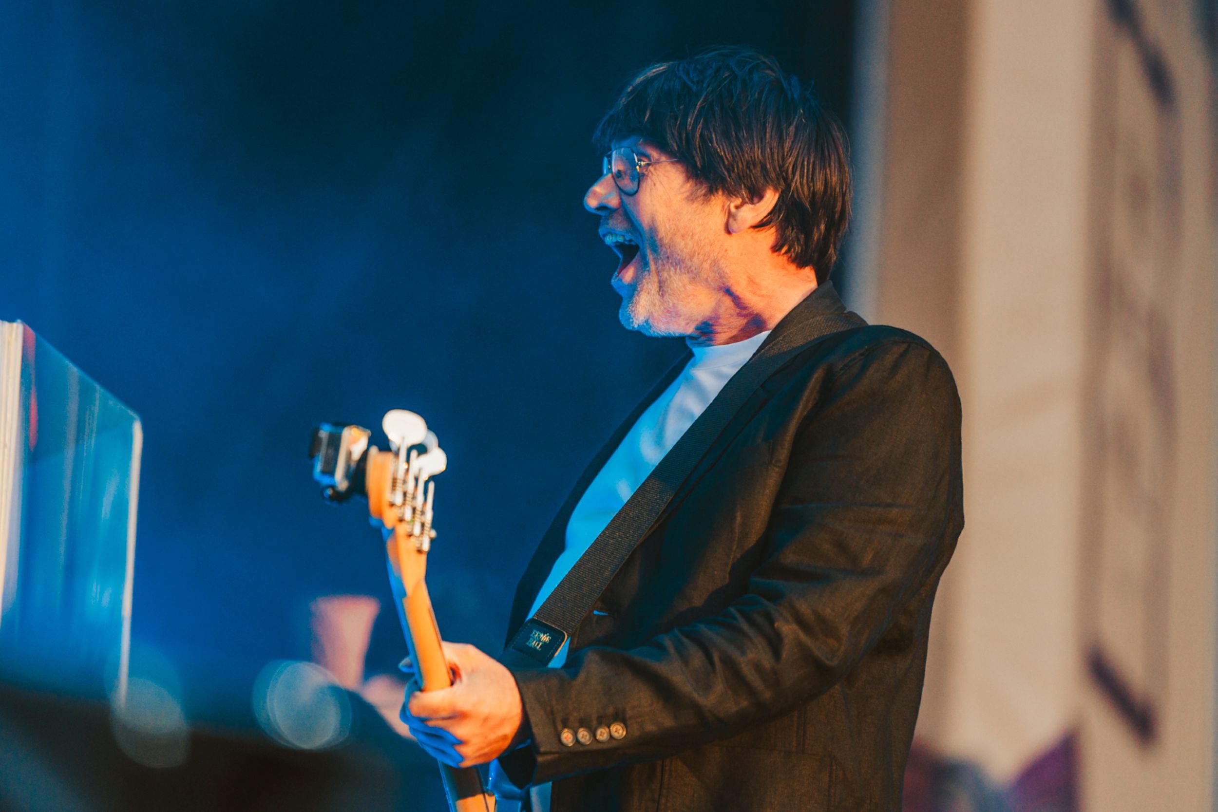 Musician playing electric guitar on stage with blue lighting