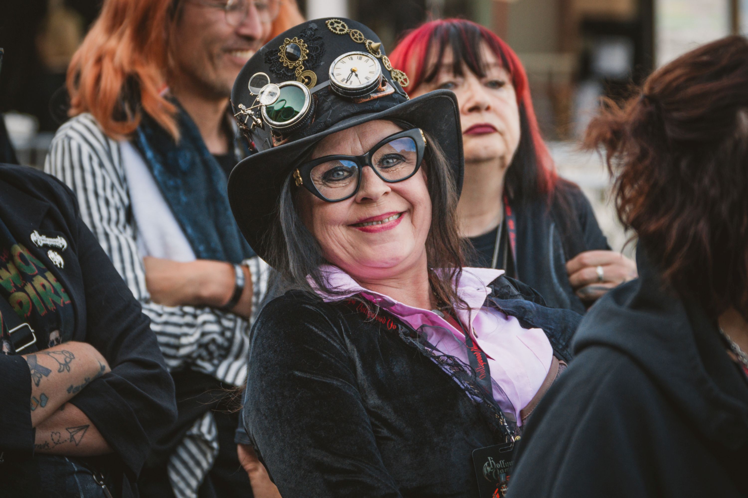 Smiling woman in steampunk attire with top hat and goggles
