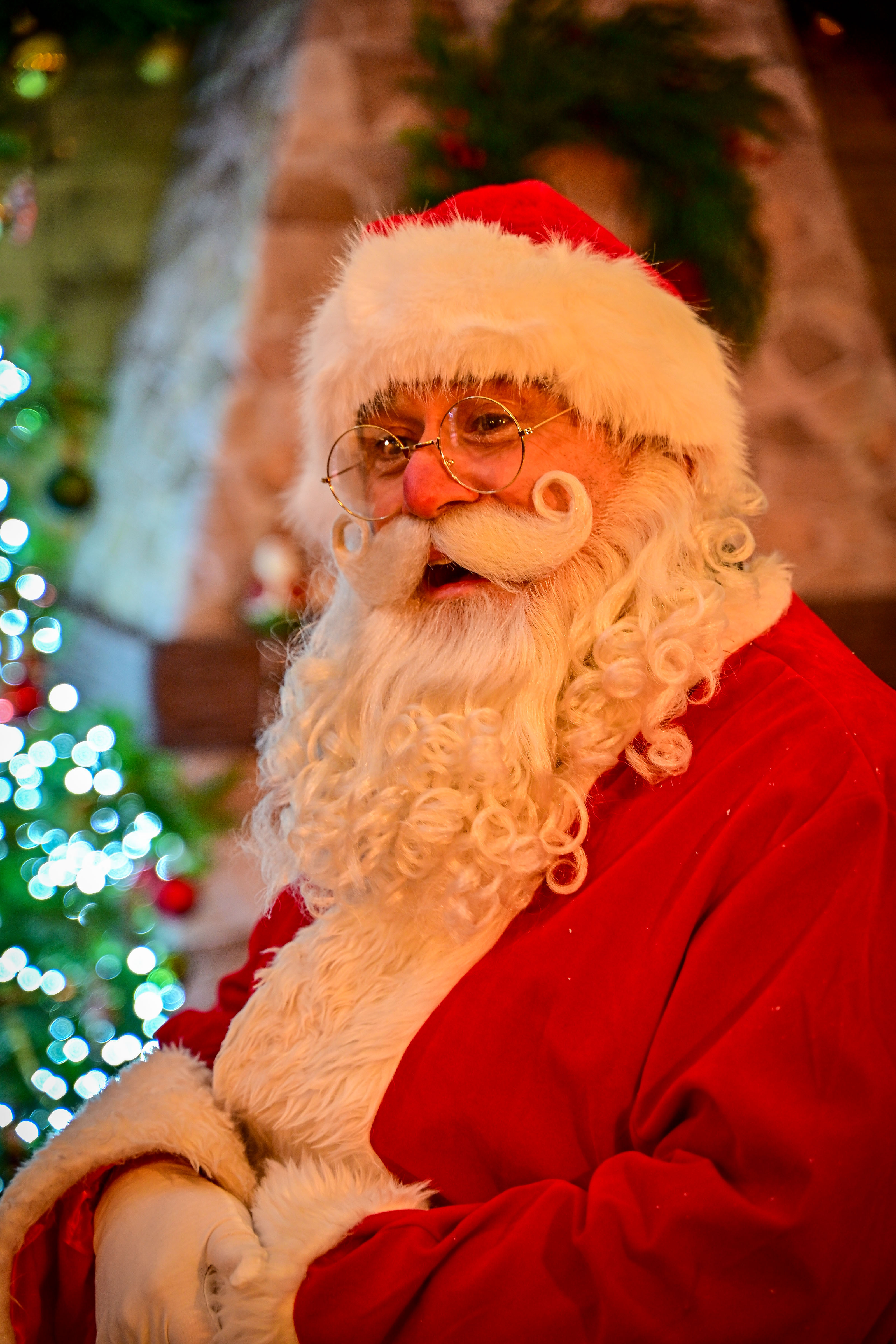 Man in Santa costume with white beard and glasses indoors